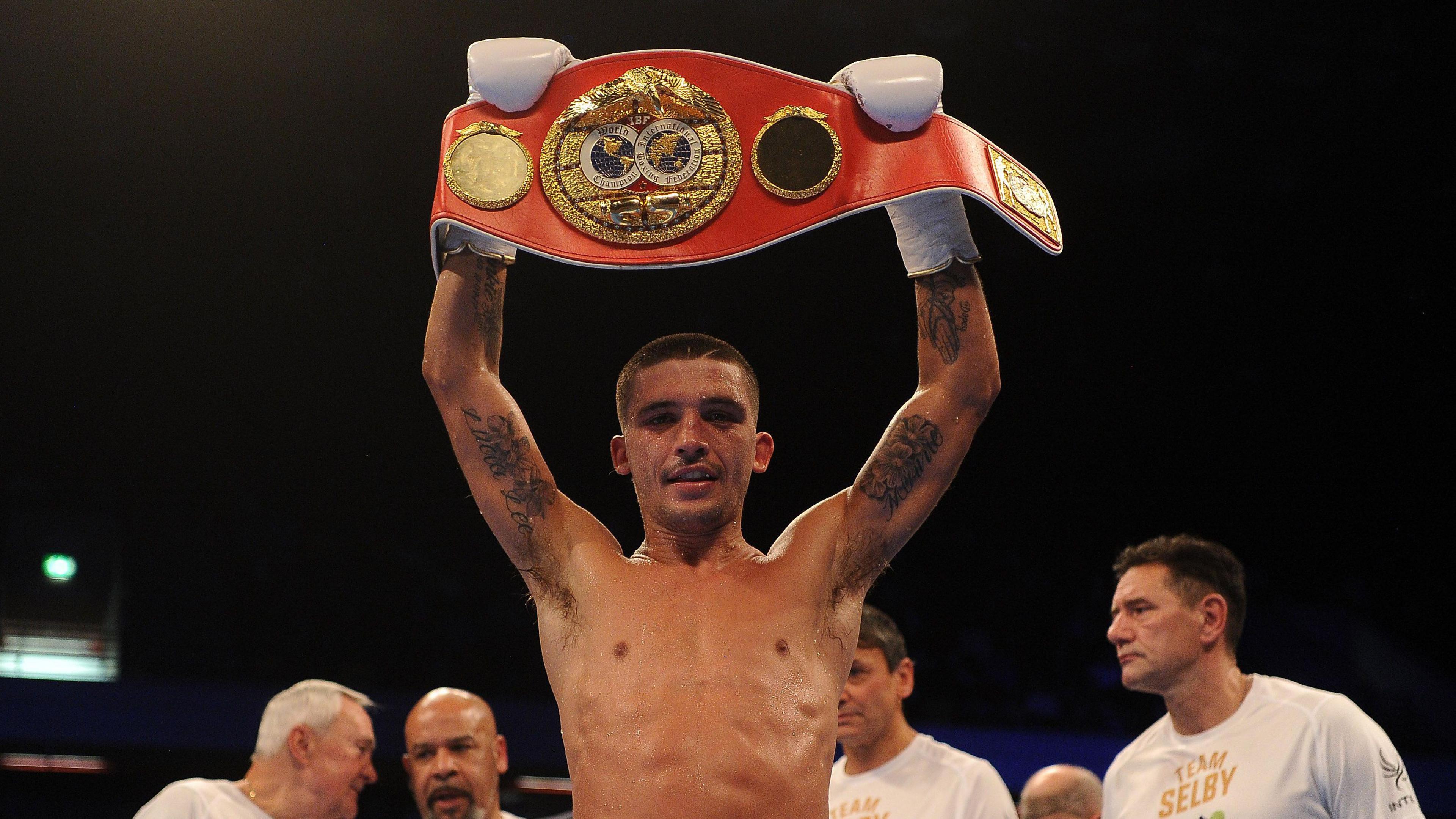 Selby holds aloft a red world title belt after a fight