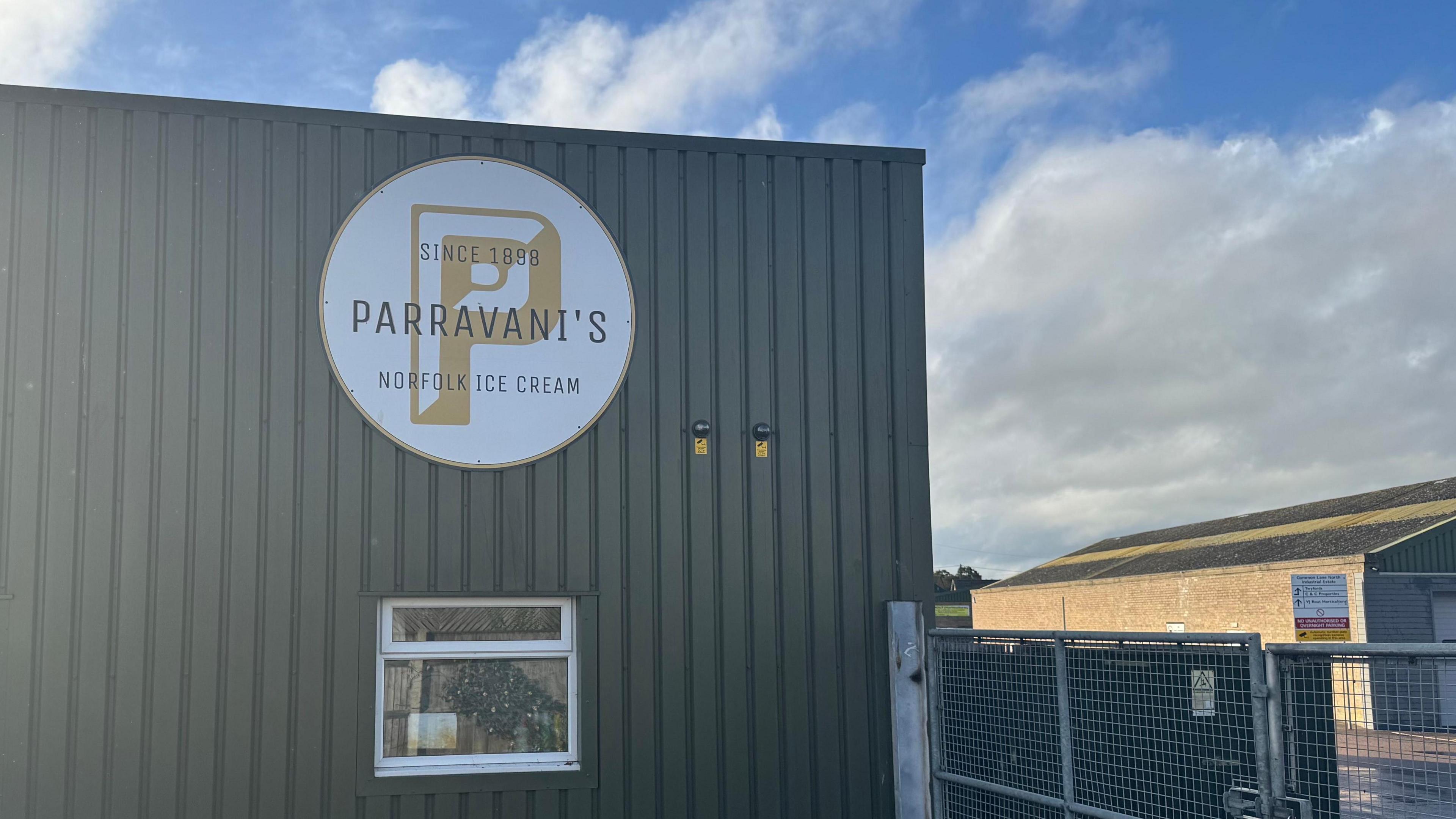 A large dark green-coloured warehouse-type unit with a large sign on it which reads Parravani's Norfolk Ice Cream.