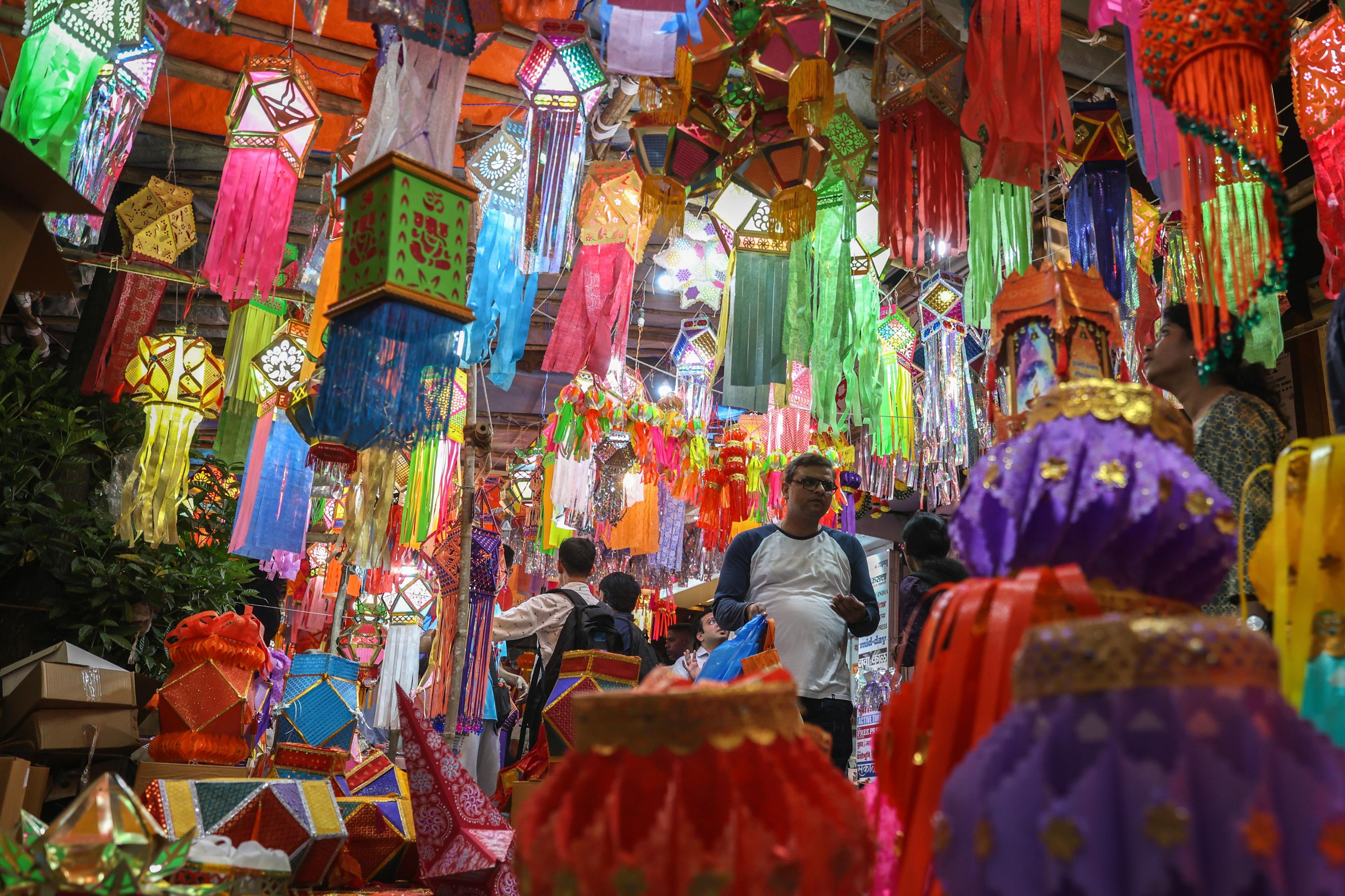 shoppers walk through a market full with lots of different lamps at different heights, some are lit