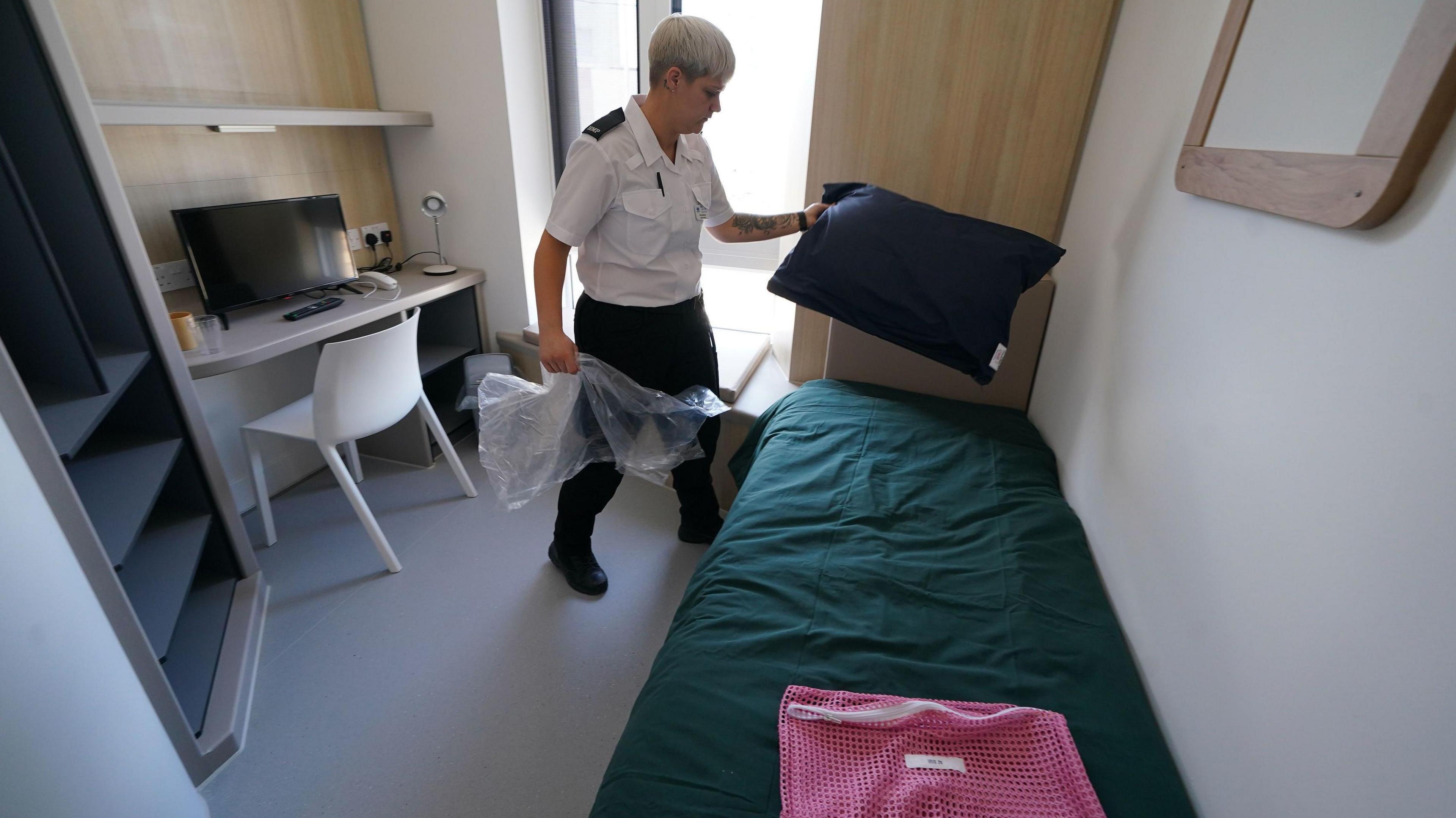 A prison officer adjusts the bedding inside a room within Iris House