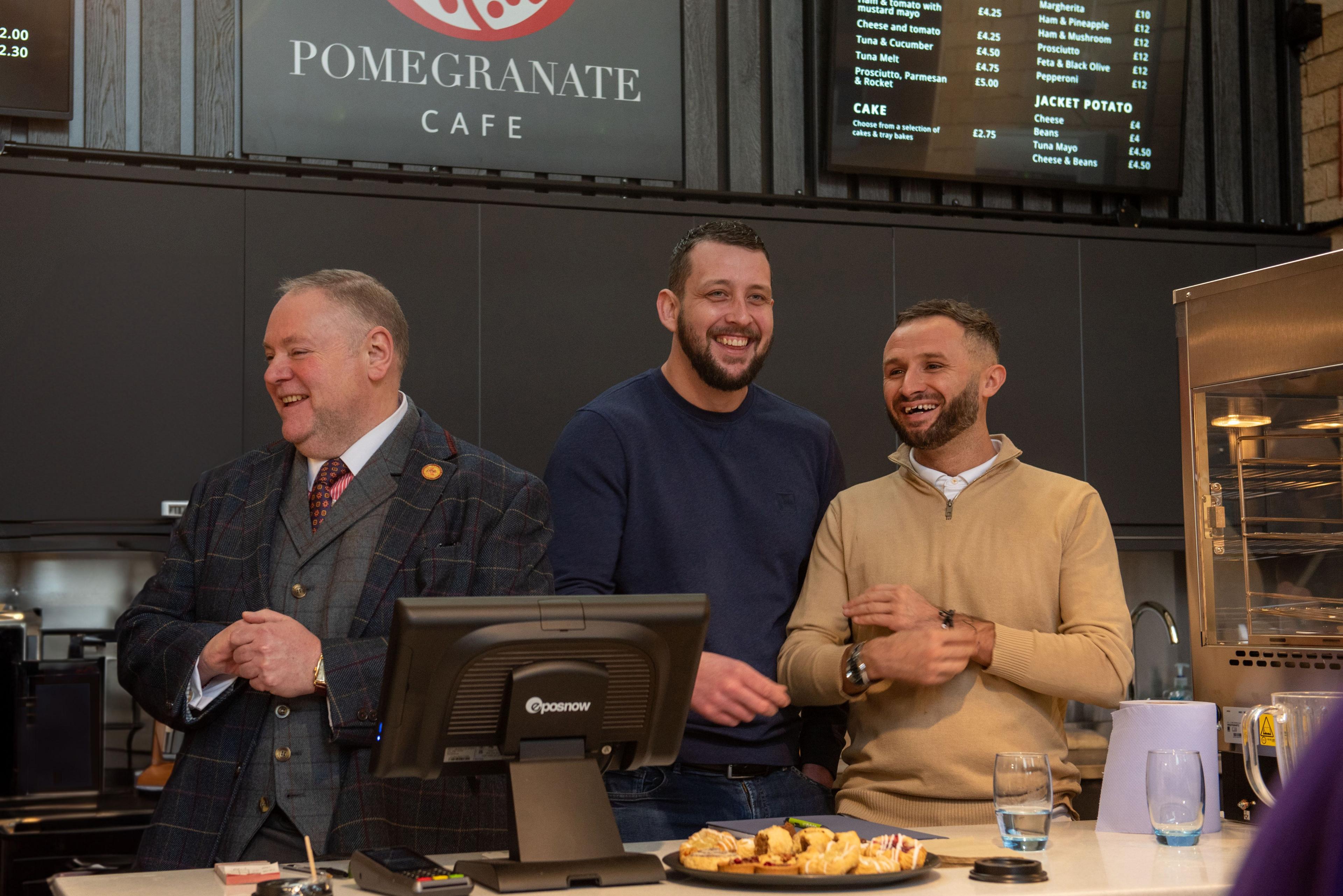 Three men behind the counter in the community café 