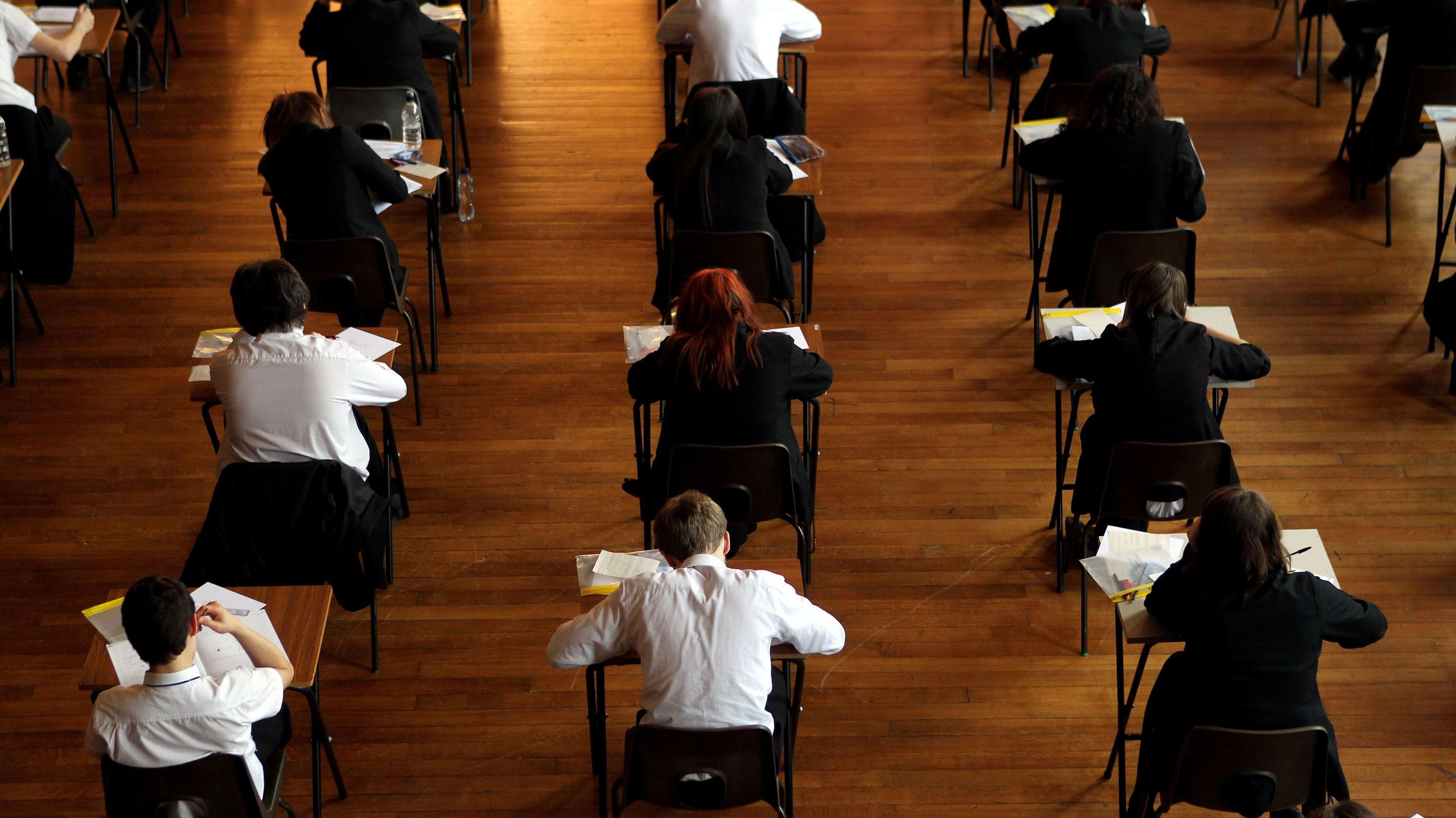 Students sat on small separate tables taking an exam