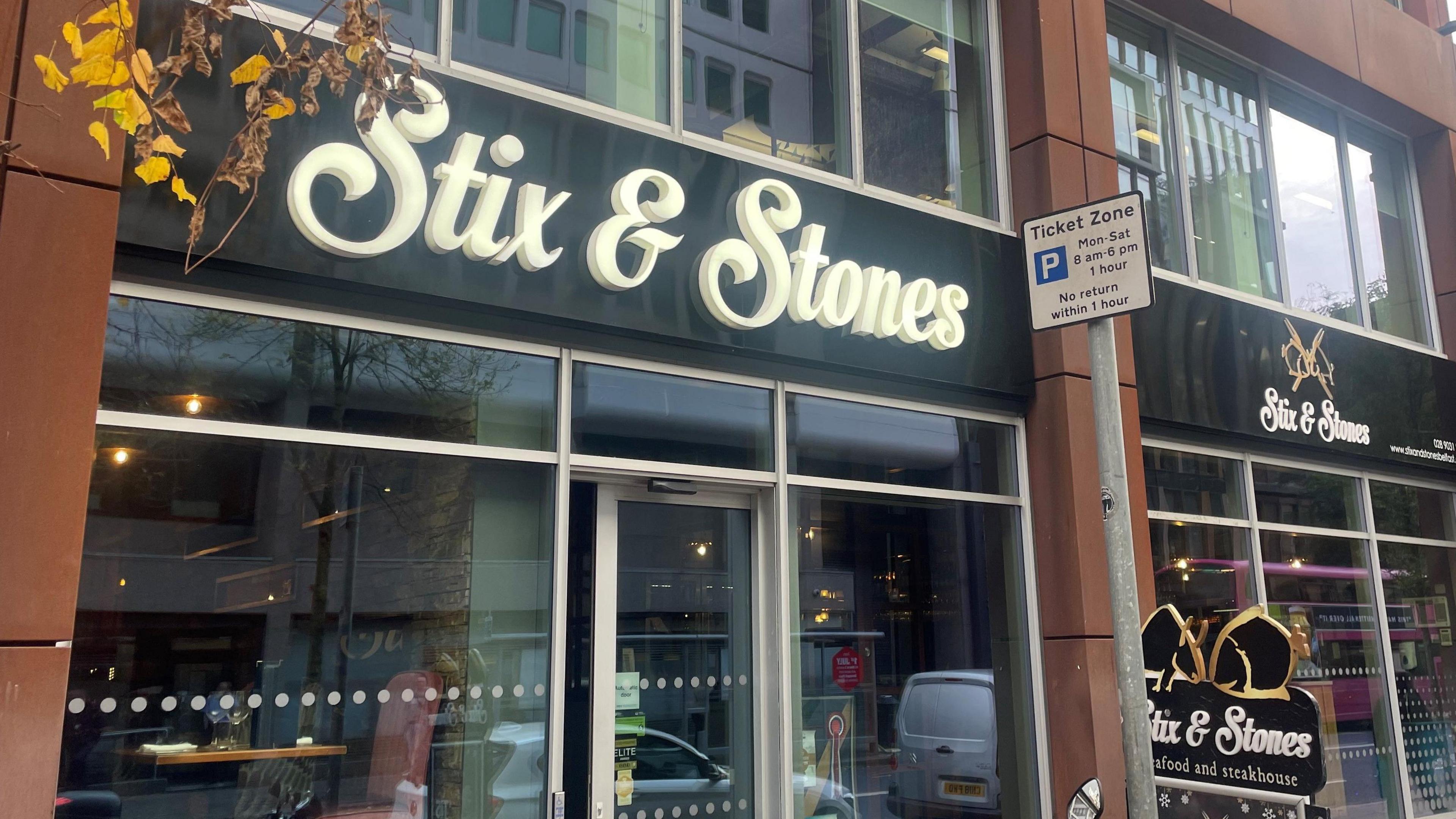 An image of Stix and Stones, a glass storefront has a black sign with white font reading "Stixs and Stones."