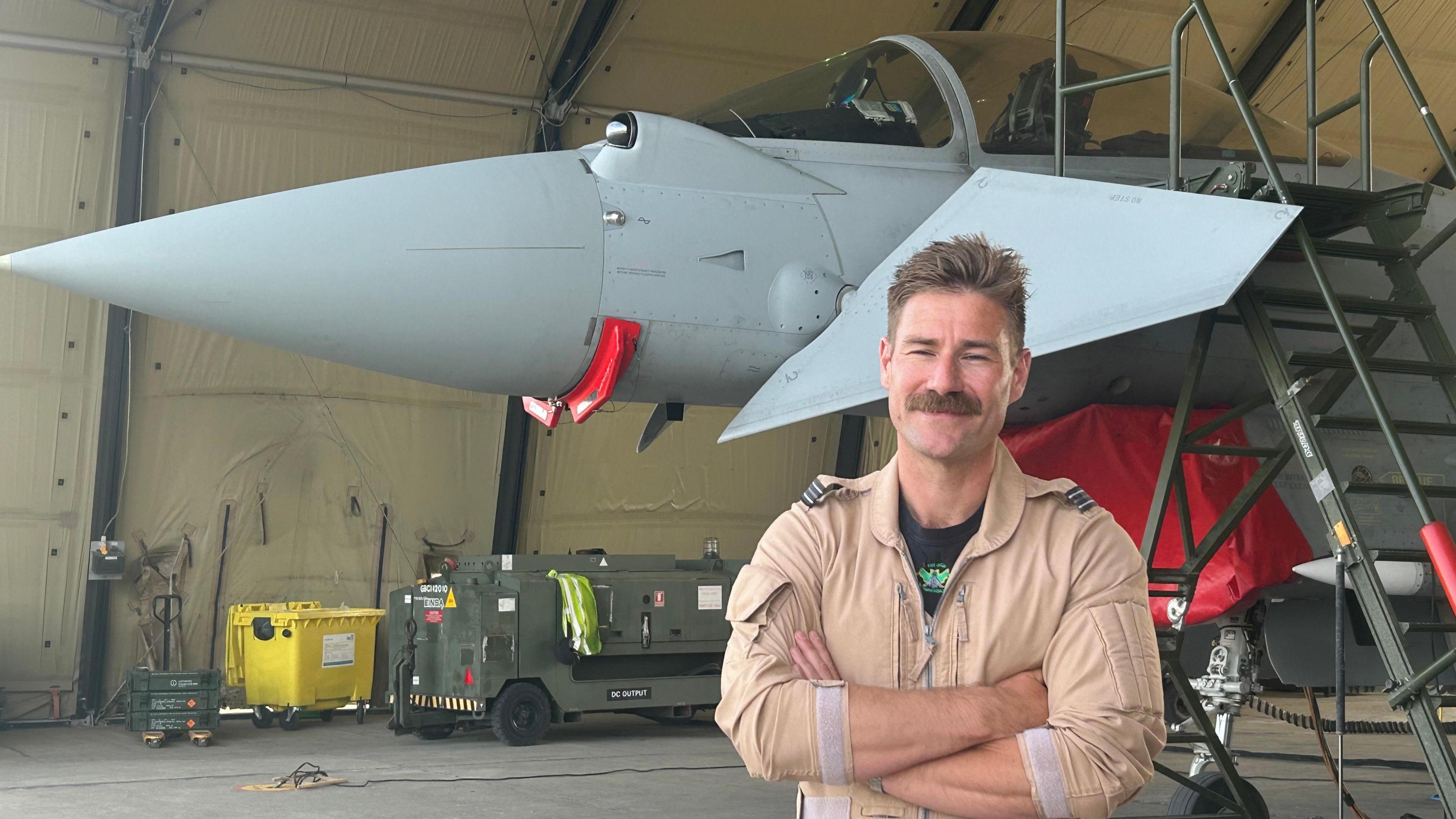 Flt Lt Charlie Tagg in front of a plane, inside a hanger