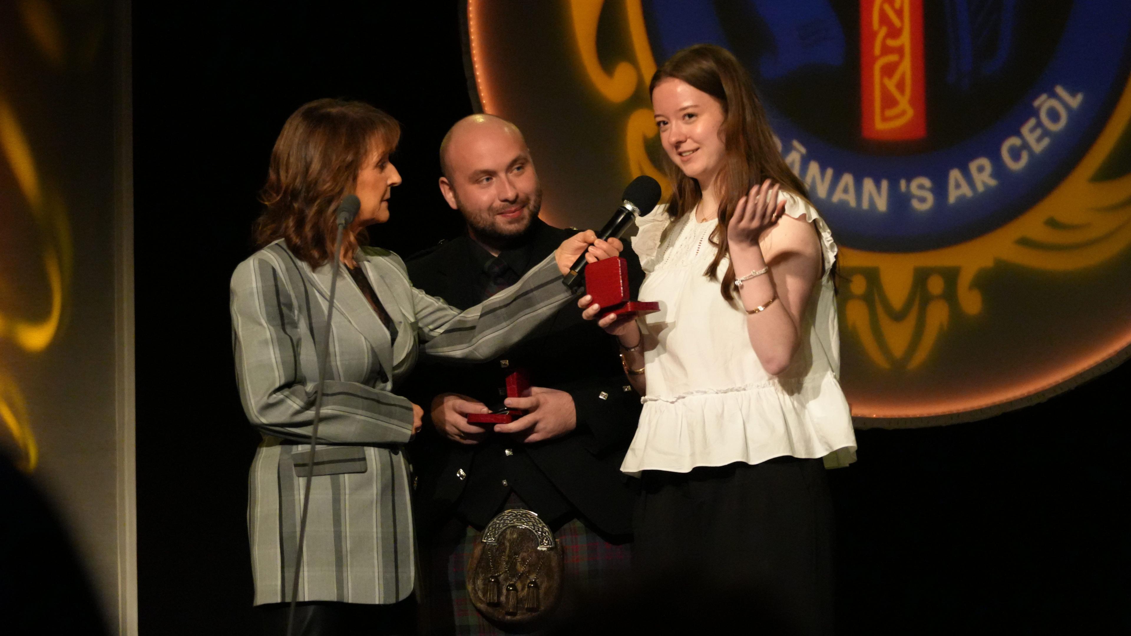 Caitlyn Yule agus Fionnlagh Iain Morse a' bruidhinn ri Angela NicFhionnghuin