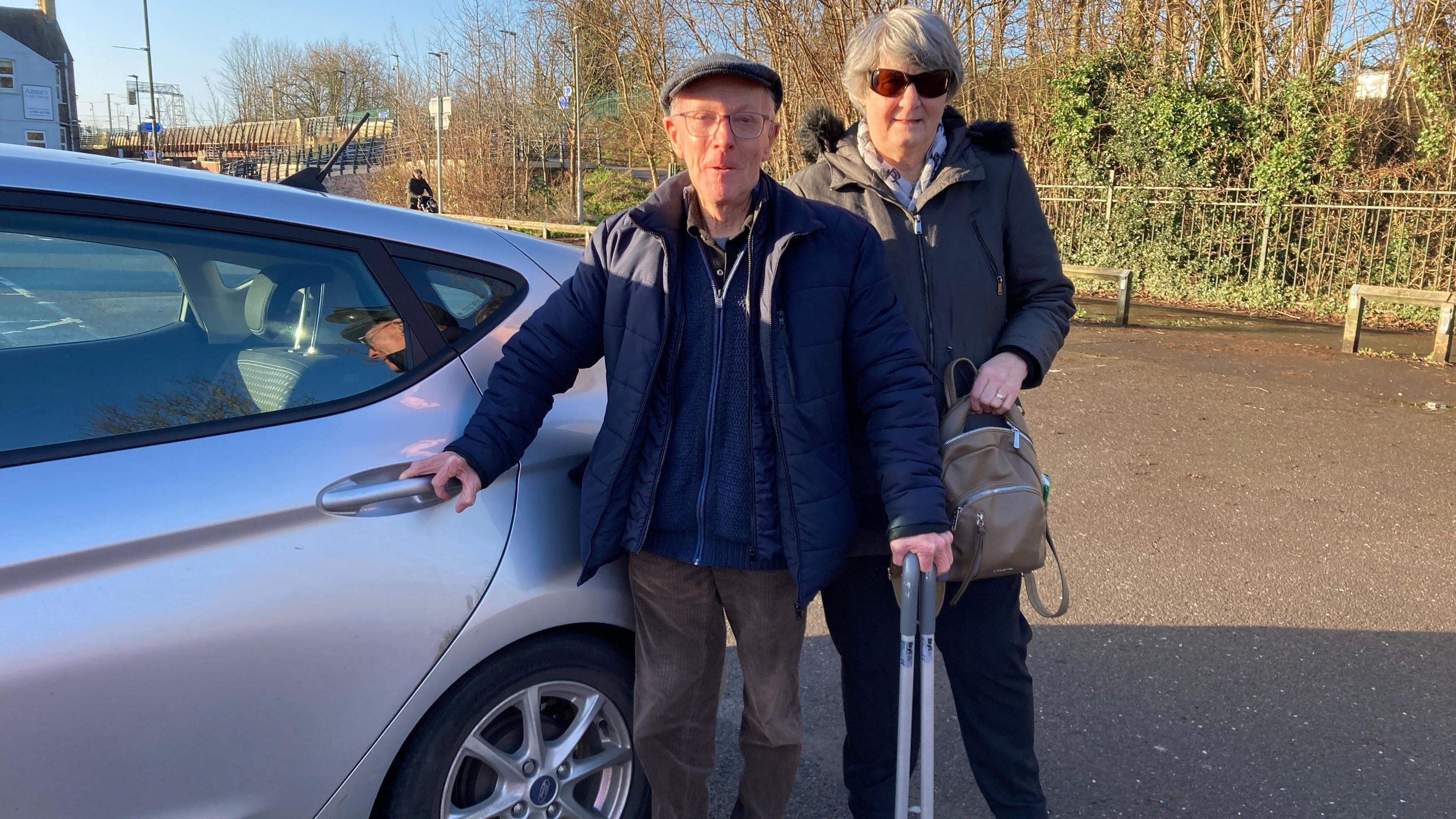 John and Gill Holman stood in front of their car