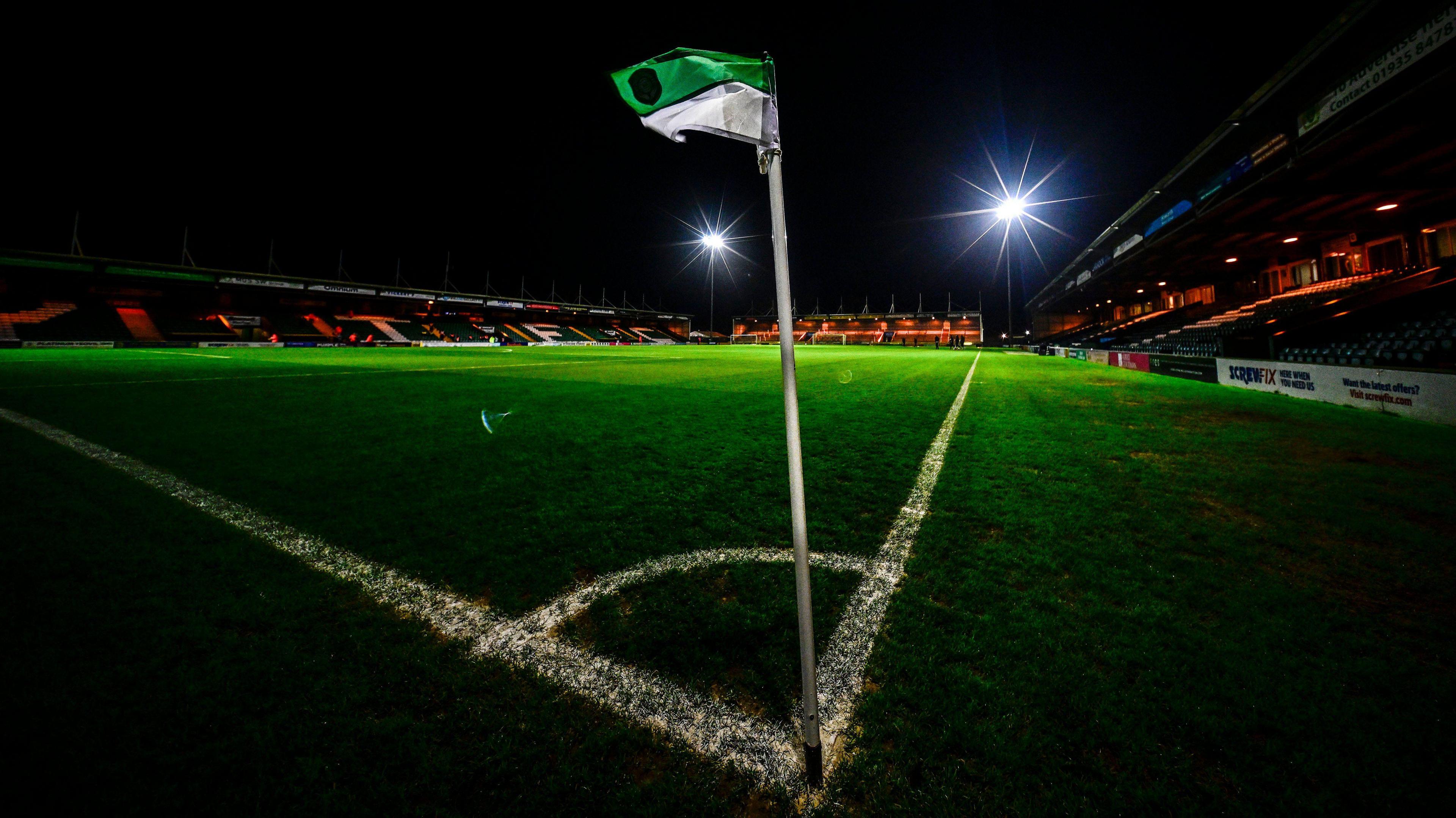 A view of a corner flag inside Huish Park in the dark before a match, with the floodlights shining