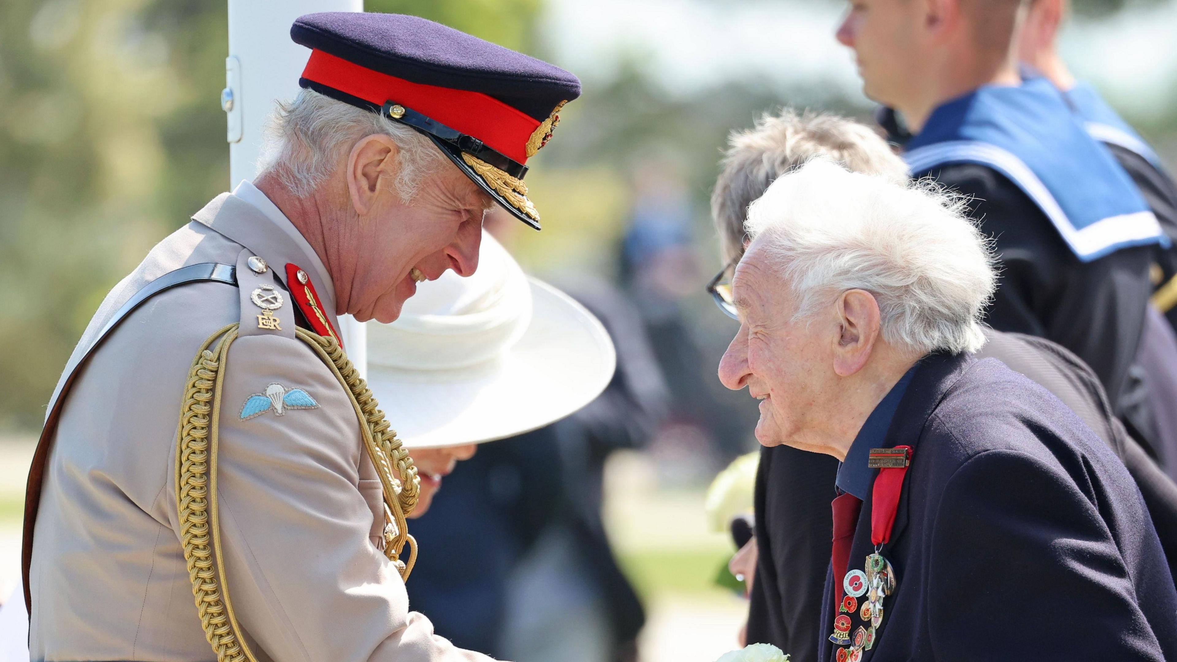 D-Day veteran Albert Keir wearing military medals shakes hands with King Charles in Normandy at D-Day commemorations, King Charles in military dress