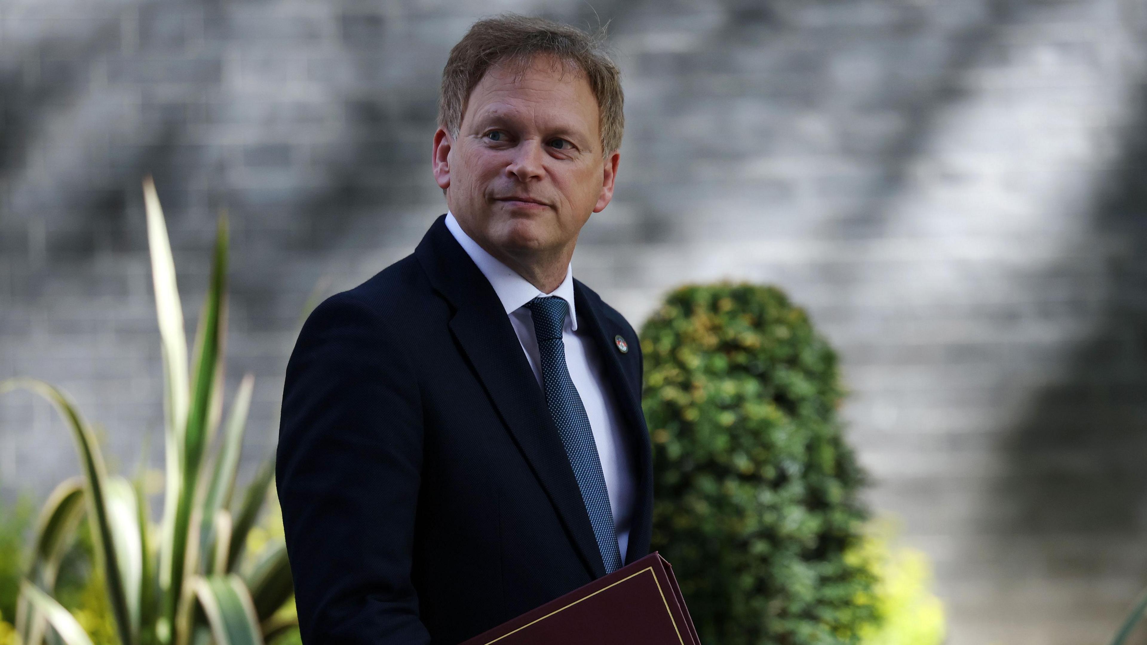 Grant Shapps walking down the road in Downing Street carrying a dark red cabinet folder