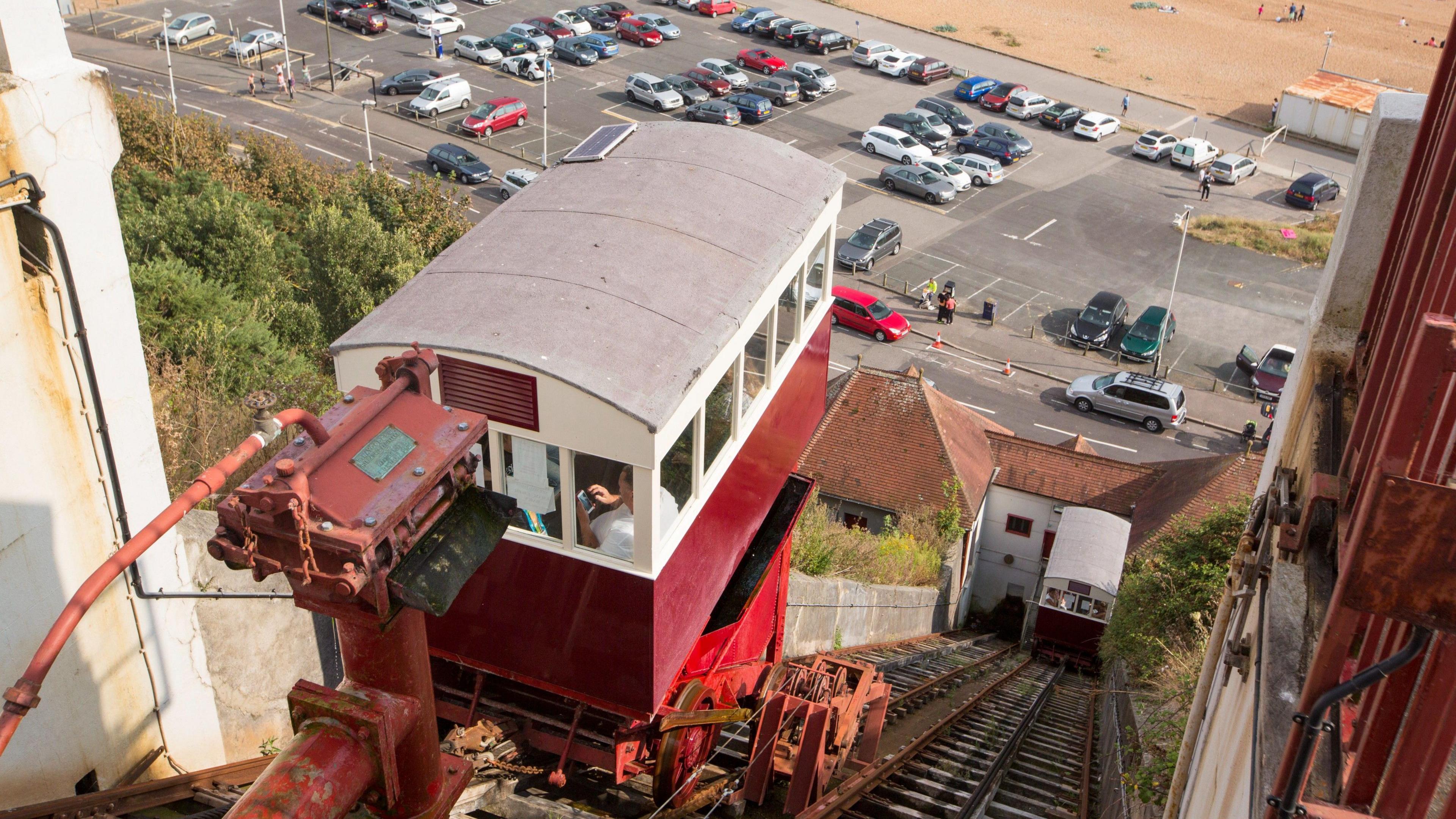 A view from the top of the Leas Lift looking down to the beach over the top of one of the red and white cars.