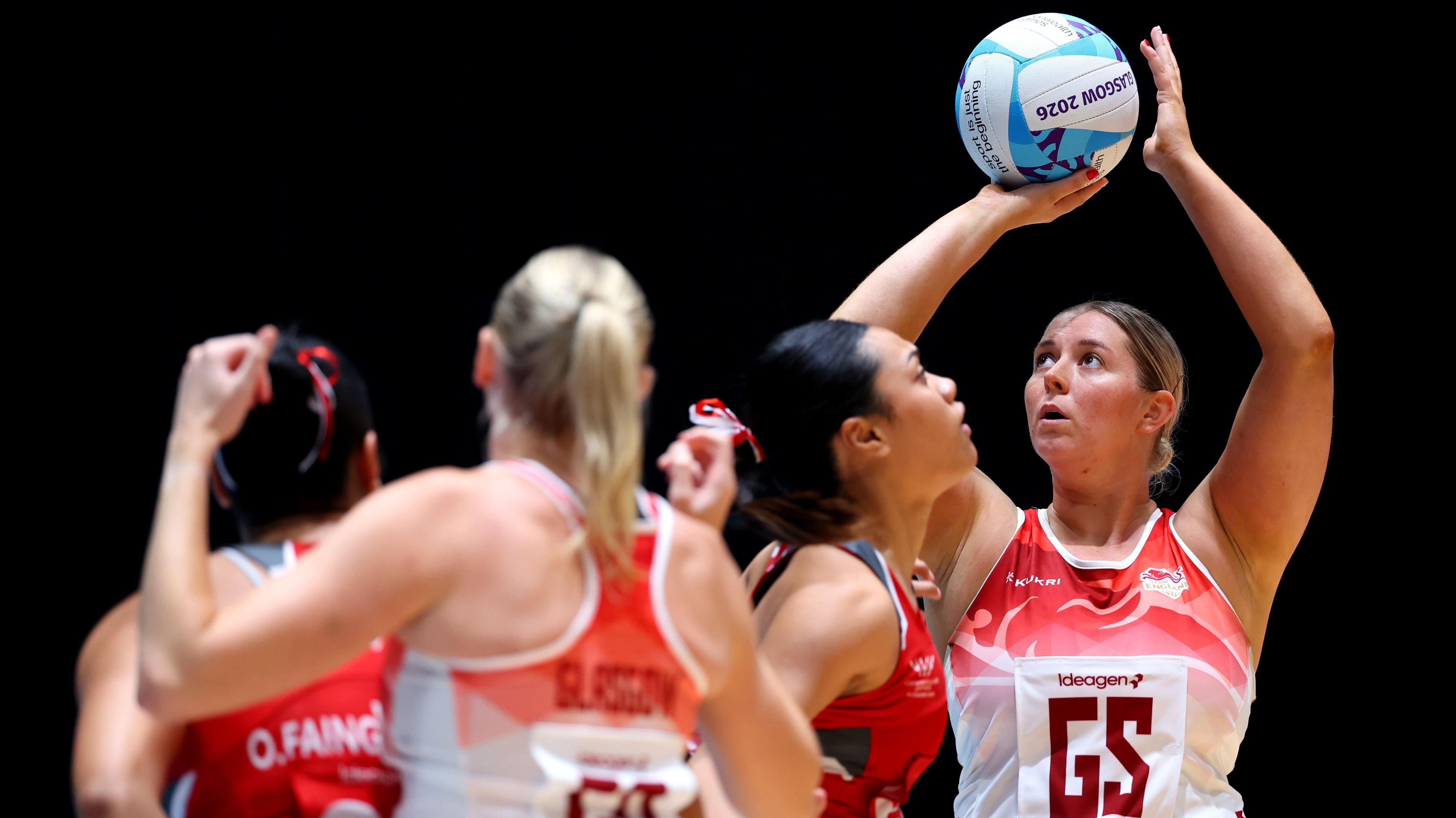 Eleanor Cardwell, wearing England's red and white netball vest top, shooting a goal in the win over Tonga at the Commonwealth Games