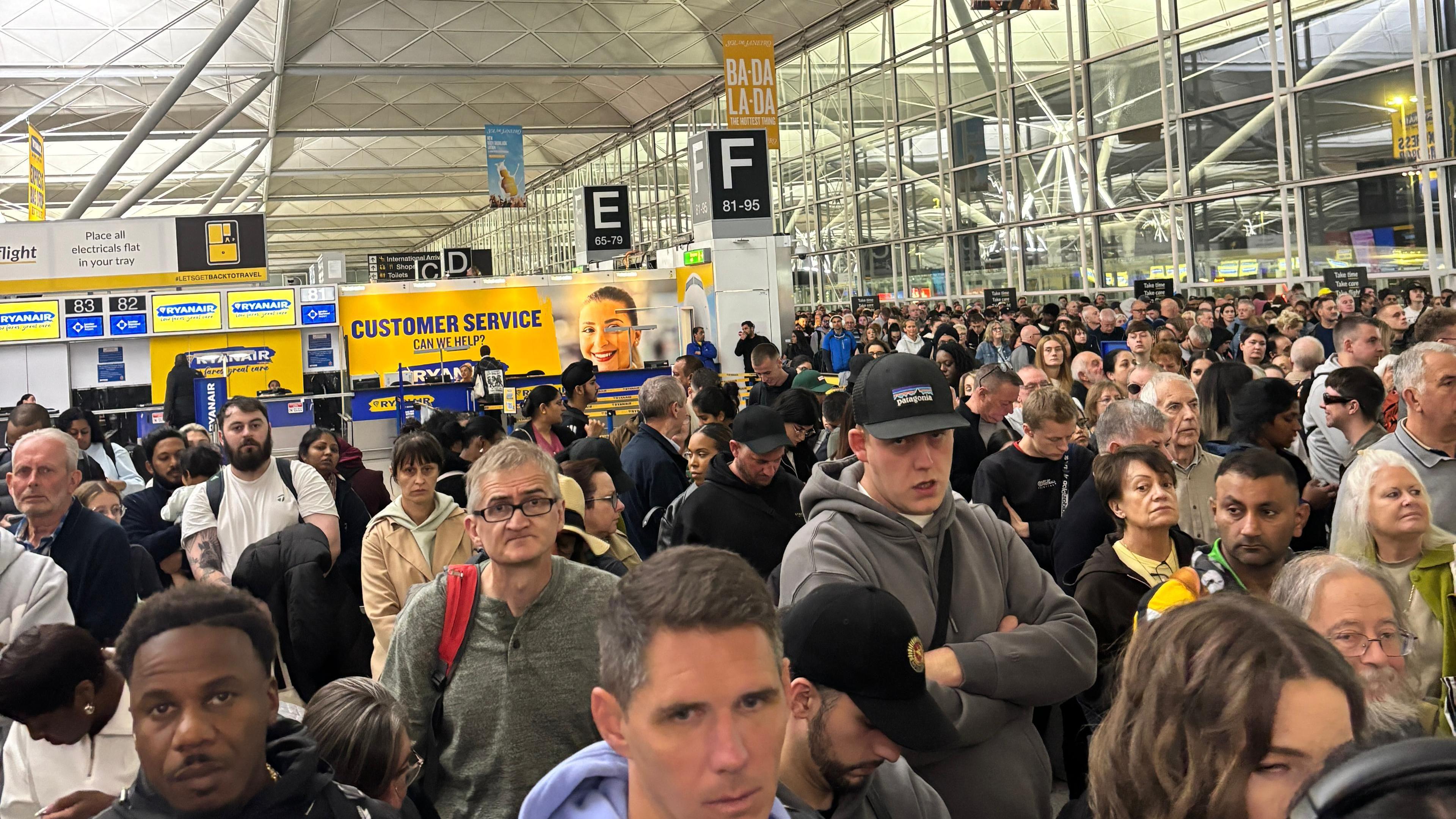 A group of people are standing together in a building. Behind them is a customer service desk for an airline.