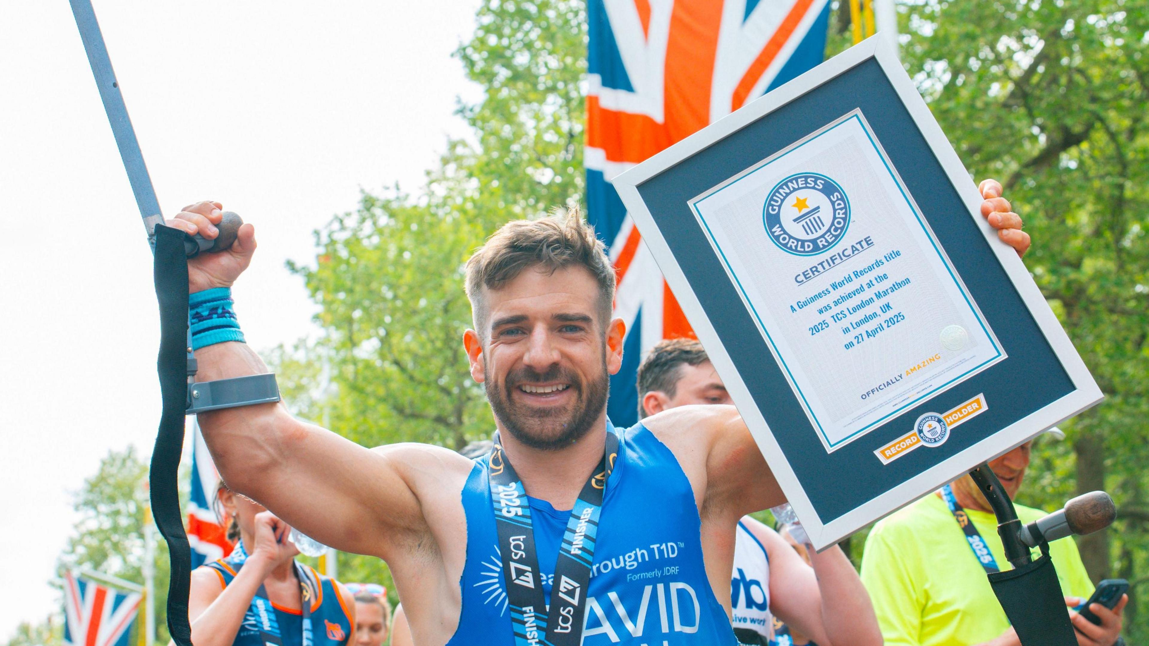 Mr Wetherill standing with one of his crutches raised in the air and holding his world record certificate.