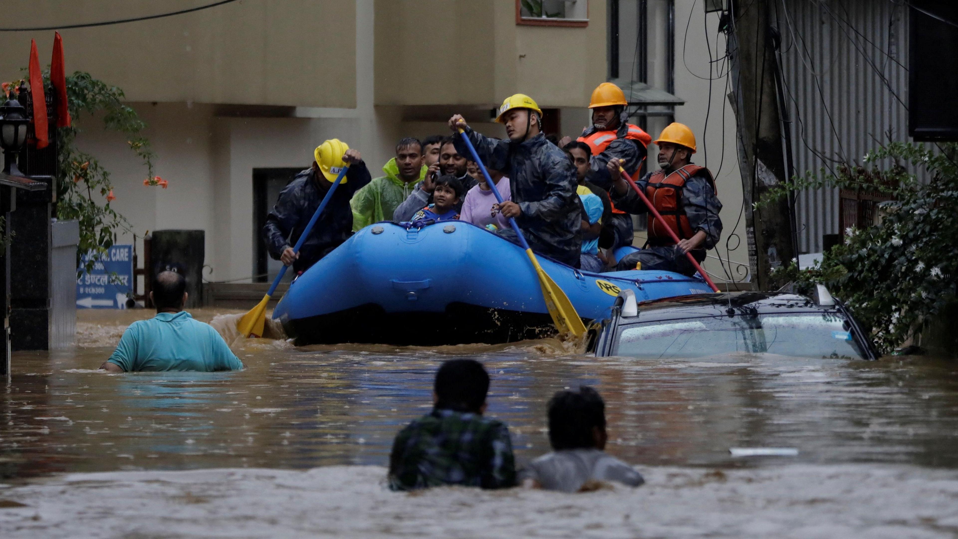 Security personnel use an inflatable raft to bring residents to safety from a flooded area near the bank of the overflowing Bagmati River following heavy rains, in Kathmandu, Nepal