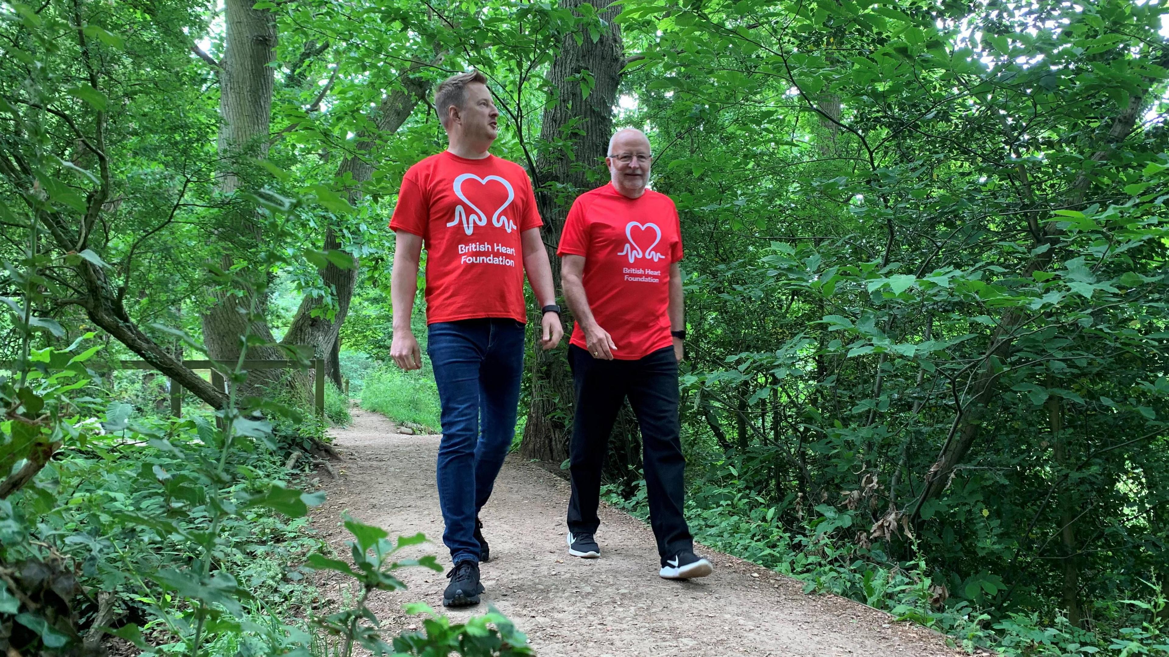 James Houghton and his dad walk side by side on a path through the forest. Both are wearing British Heart Foundation t-shirts.