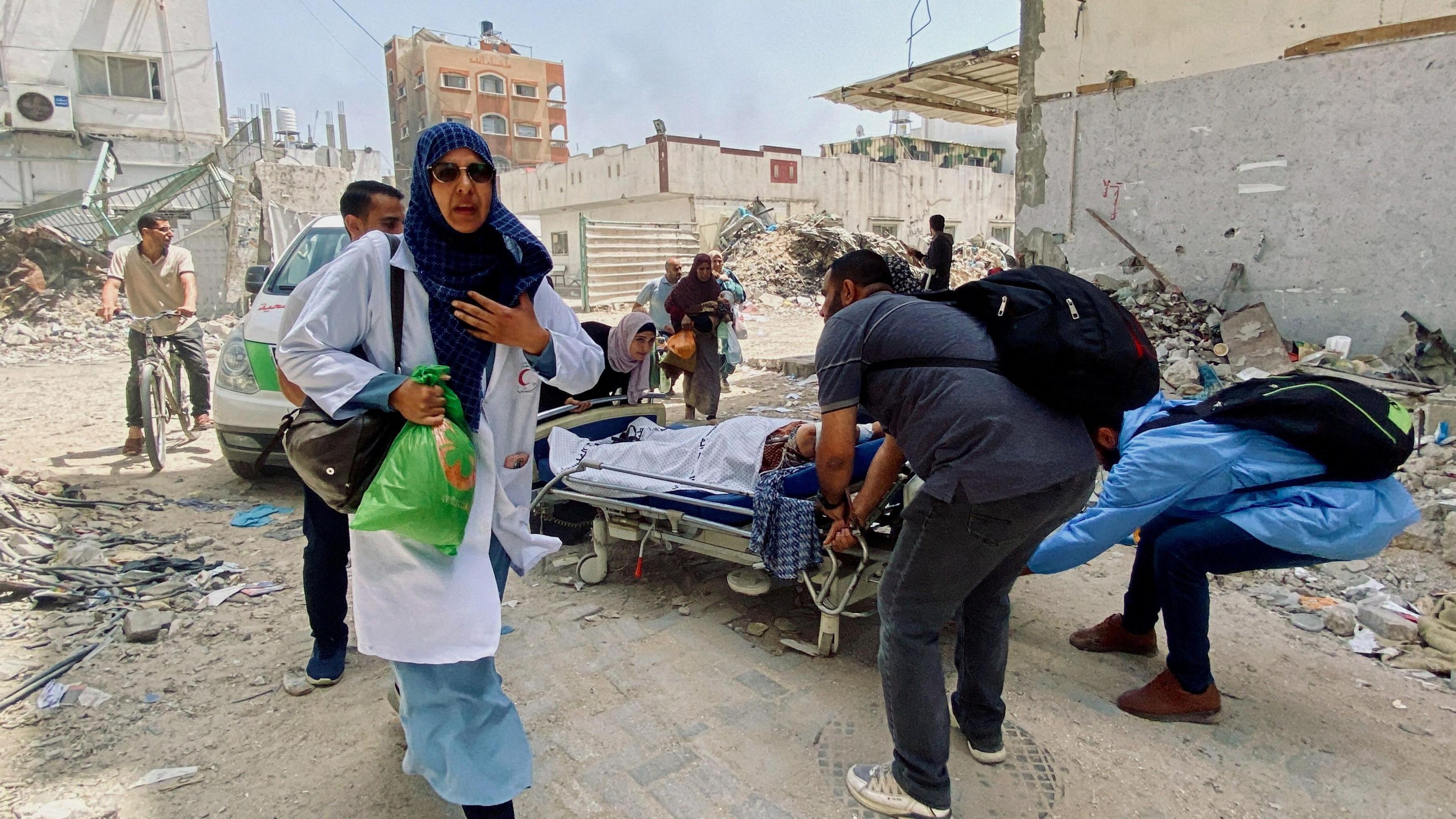 Palestinian medics and patients evacuate the Kamal Adwan hospital in Beit Lahia, northern Gaza, following a strike on 21 May 2024