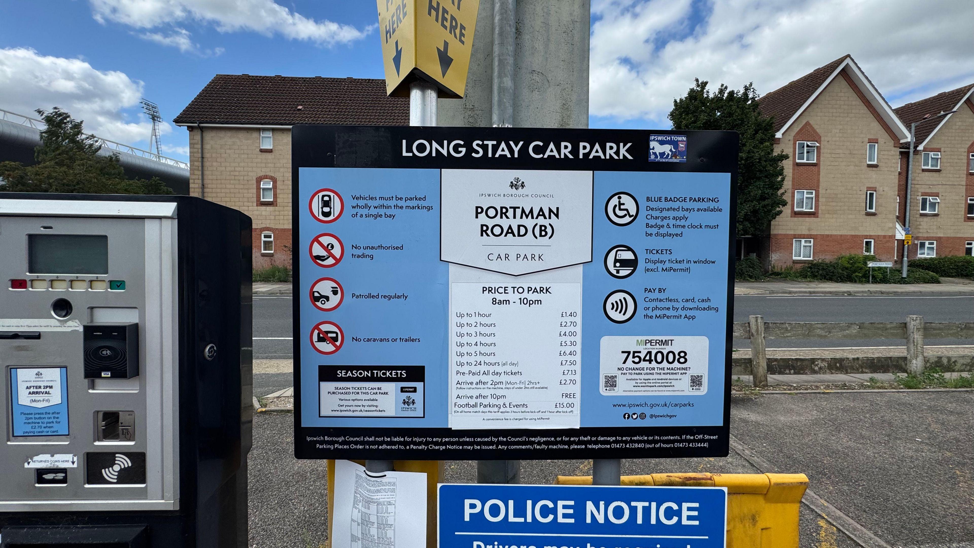 A parking sign in a car park. It includes the prices.