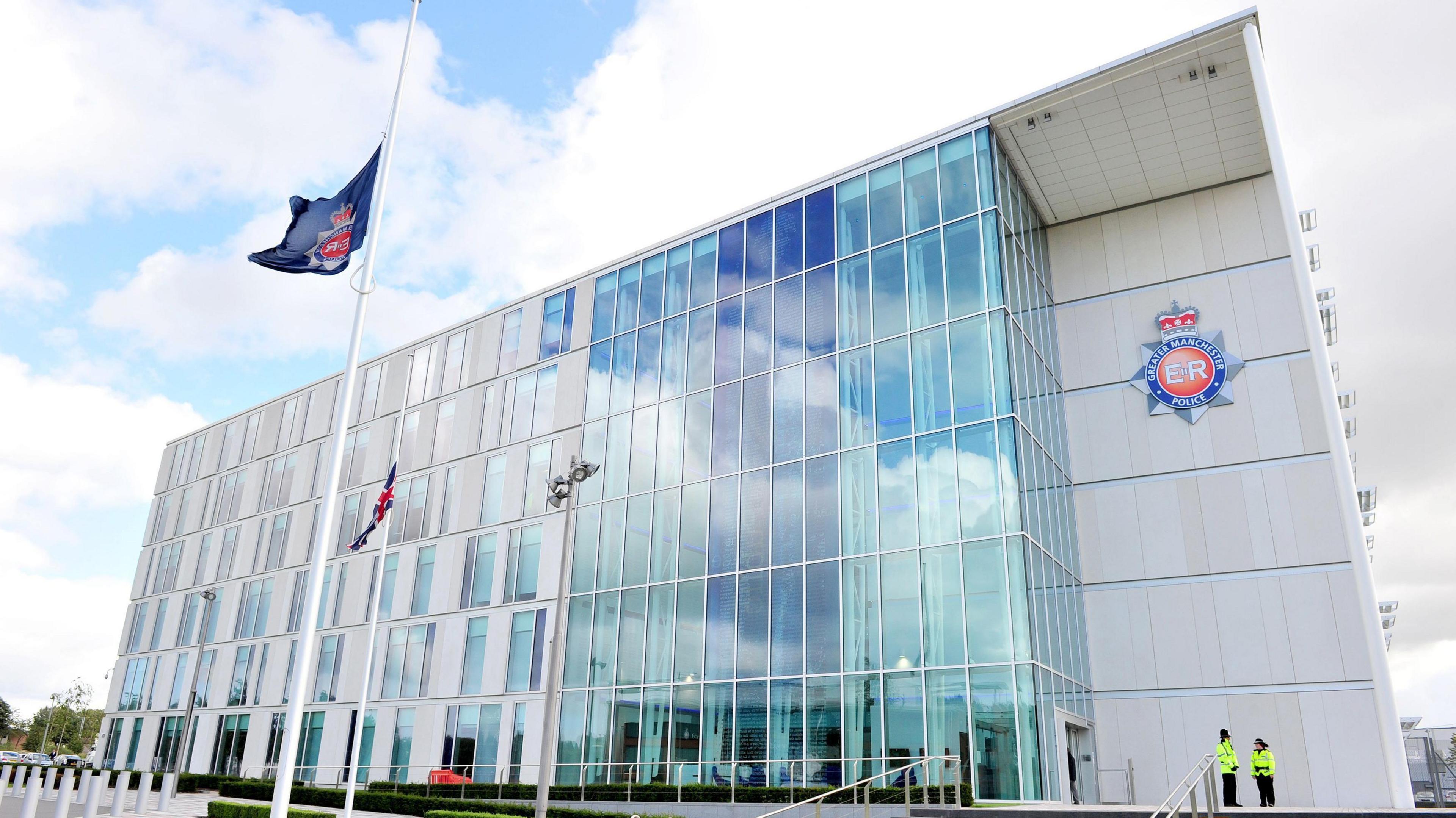 Greater Manchester Police headquarters is a large, six-storey glass-fronted building. It has the force's logo high on the right-hand wall.