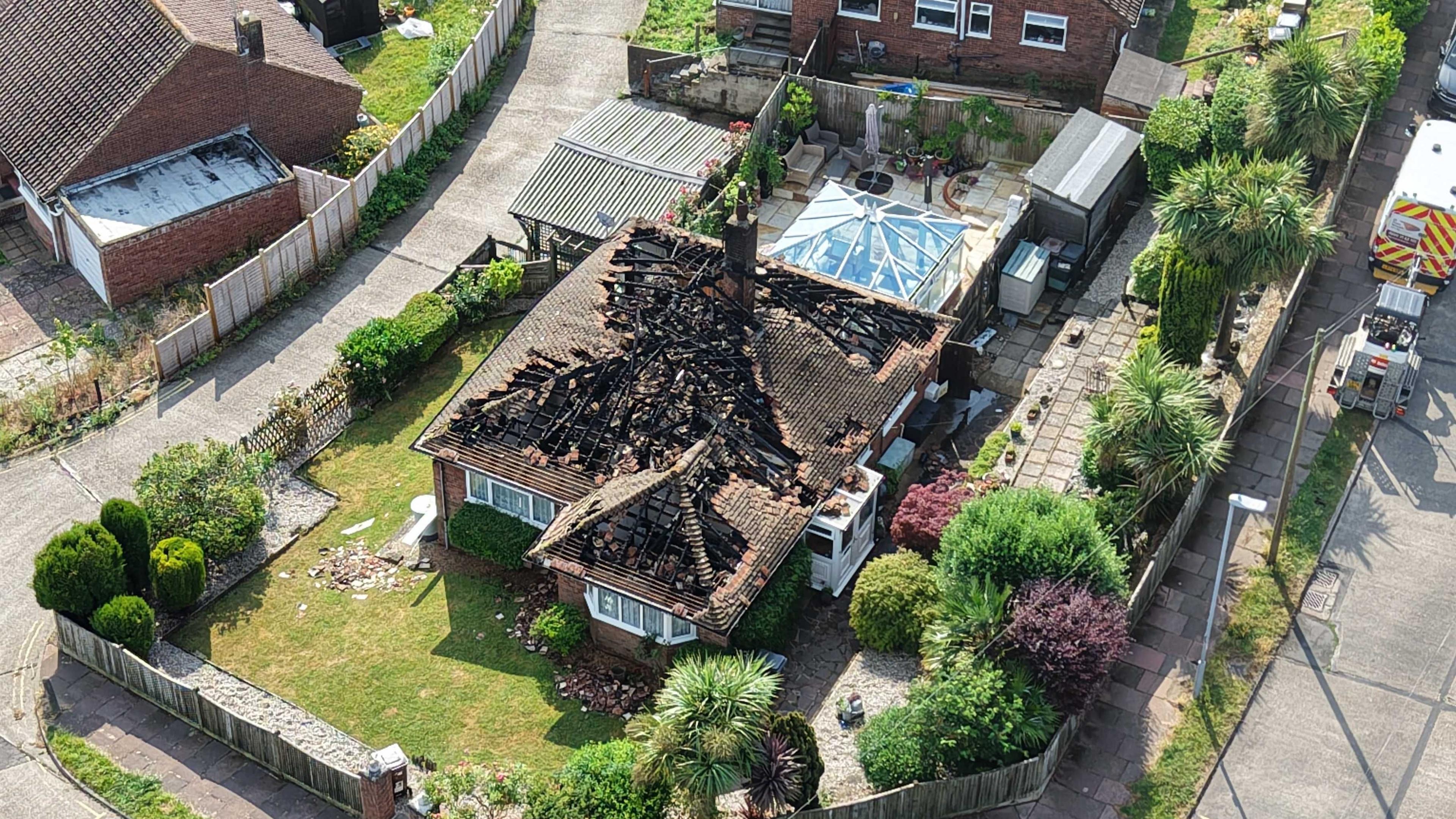 An aerial shot of a house with a heavily damaged roof.