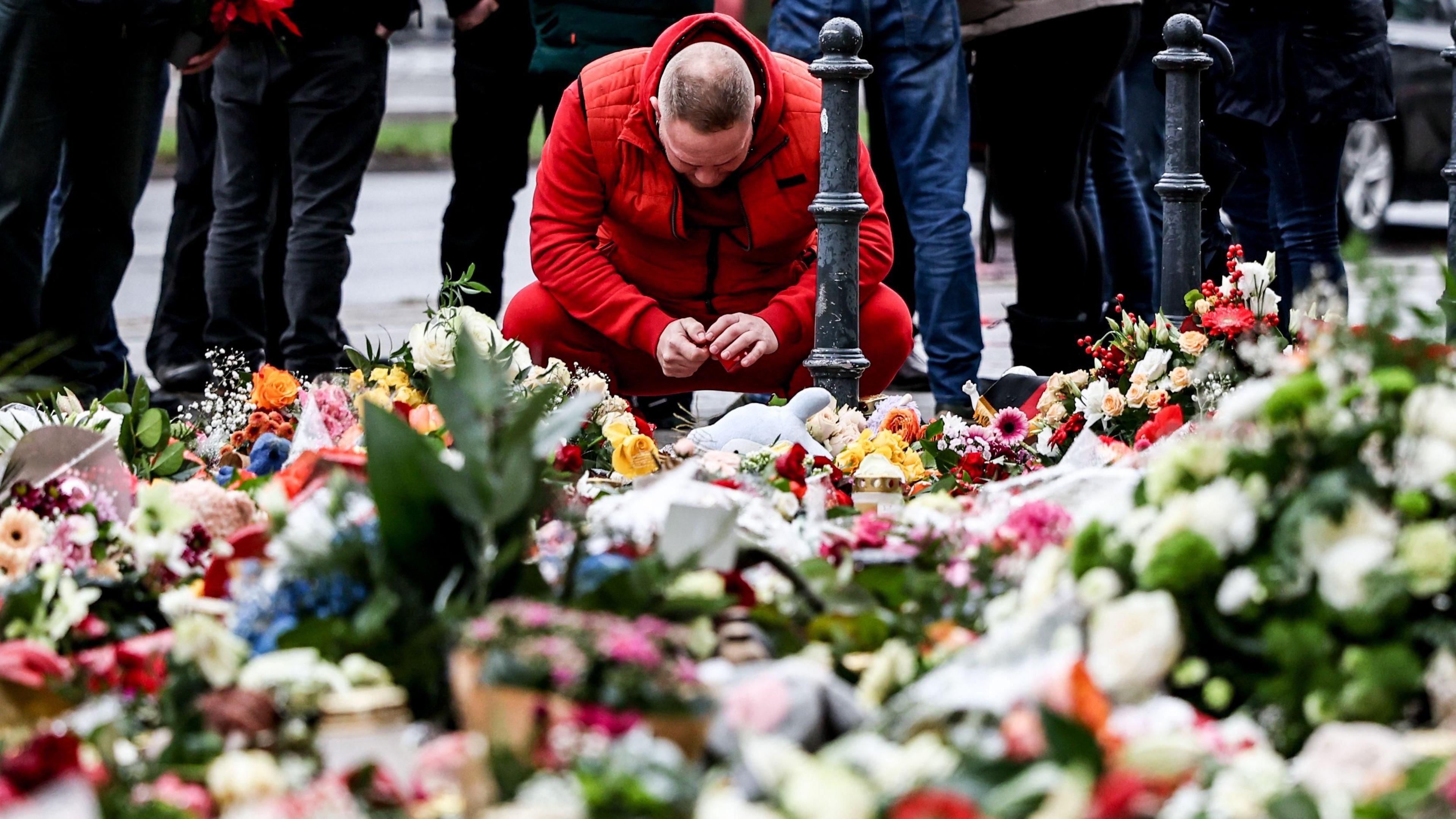 A man mourns at the mourning site in front of St. John's Church following a vehicle-ramming attack on the Christmas market in Magdeburg, Germany,  22 December 2024