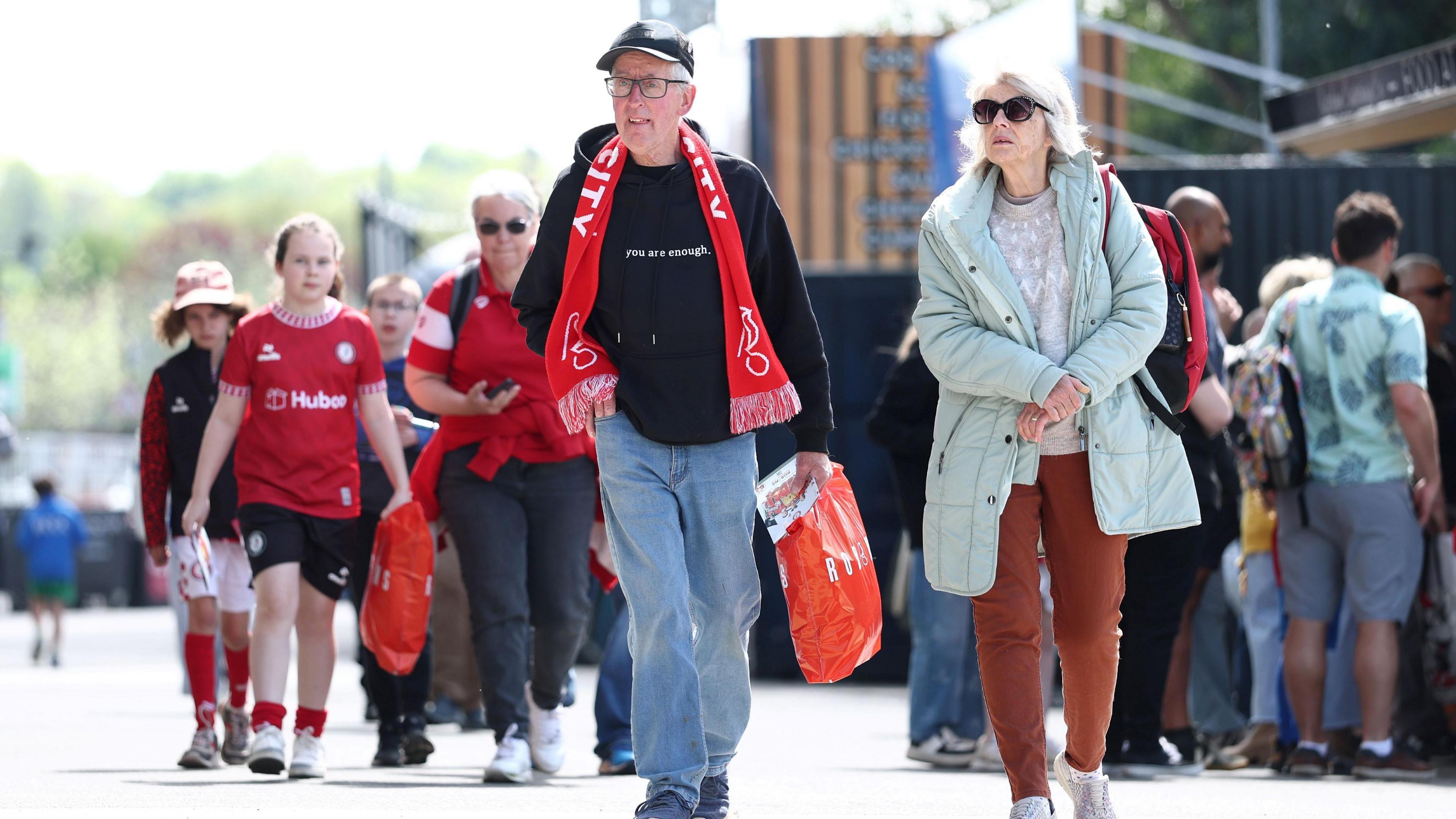 Bristol City Women's FC fans, some wearing red replica tops and some wearing red and white scarves, walk towards Ashton Gate Stadium before the game with Sunderland