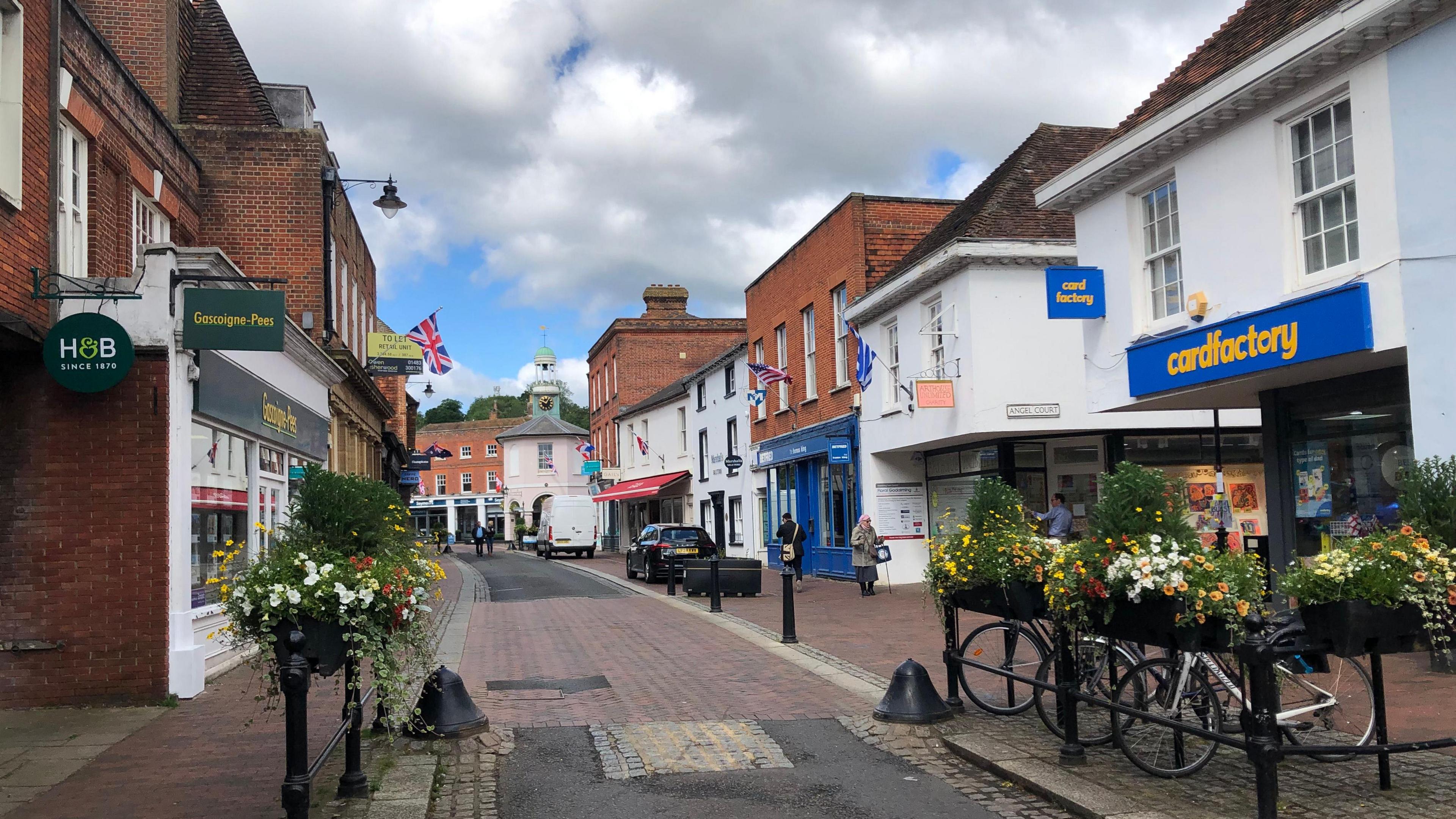 Town of Godalming, high street, cars, bikes, shops, flowers