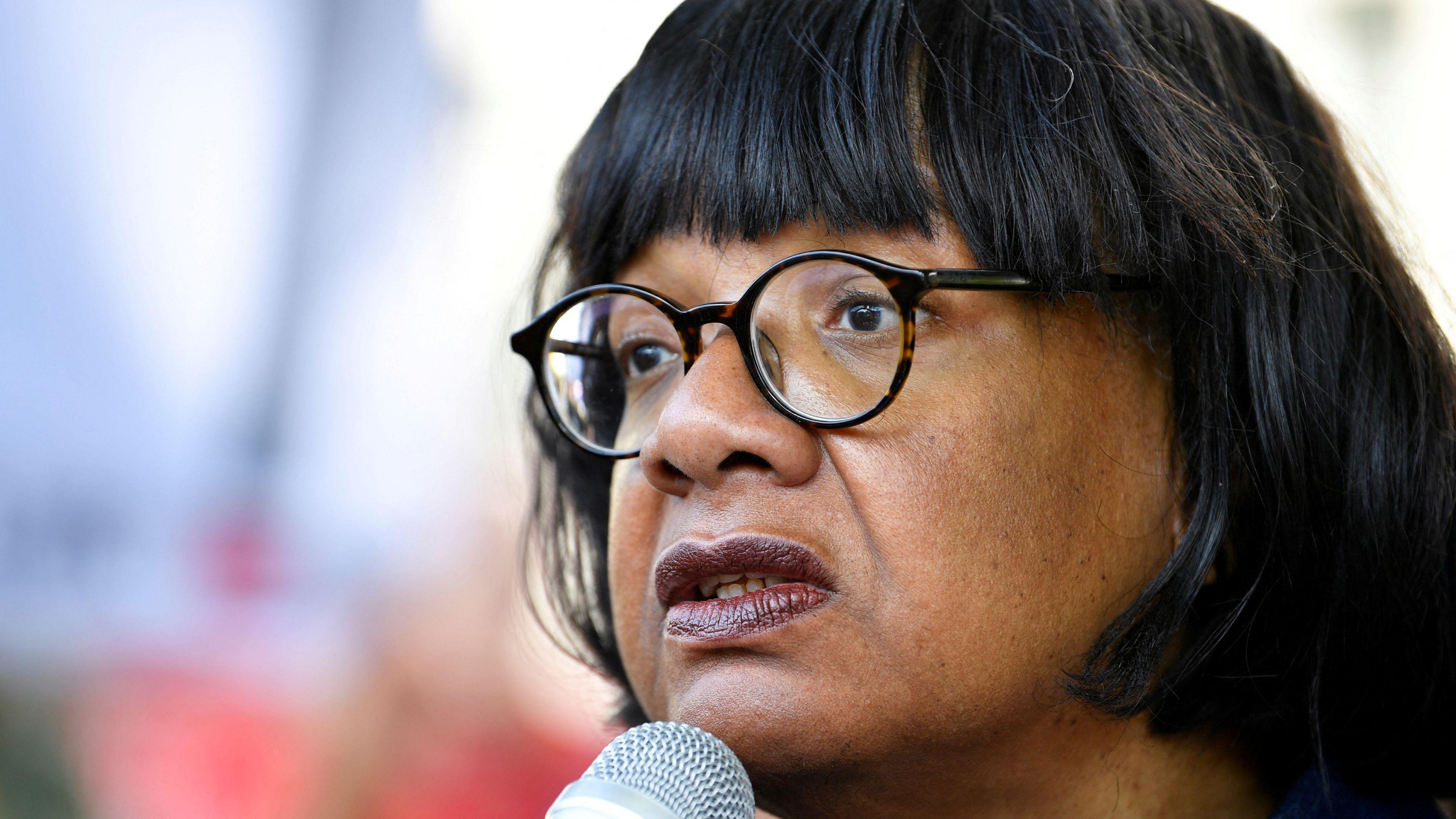 Diane Abbott, who has medium length dark hair and round glasses, speaking into a microphone.