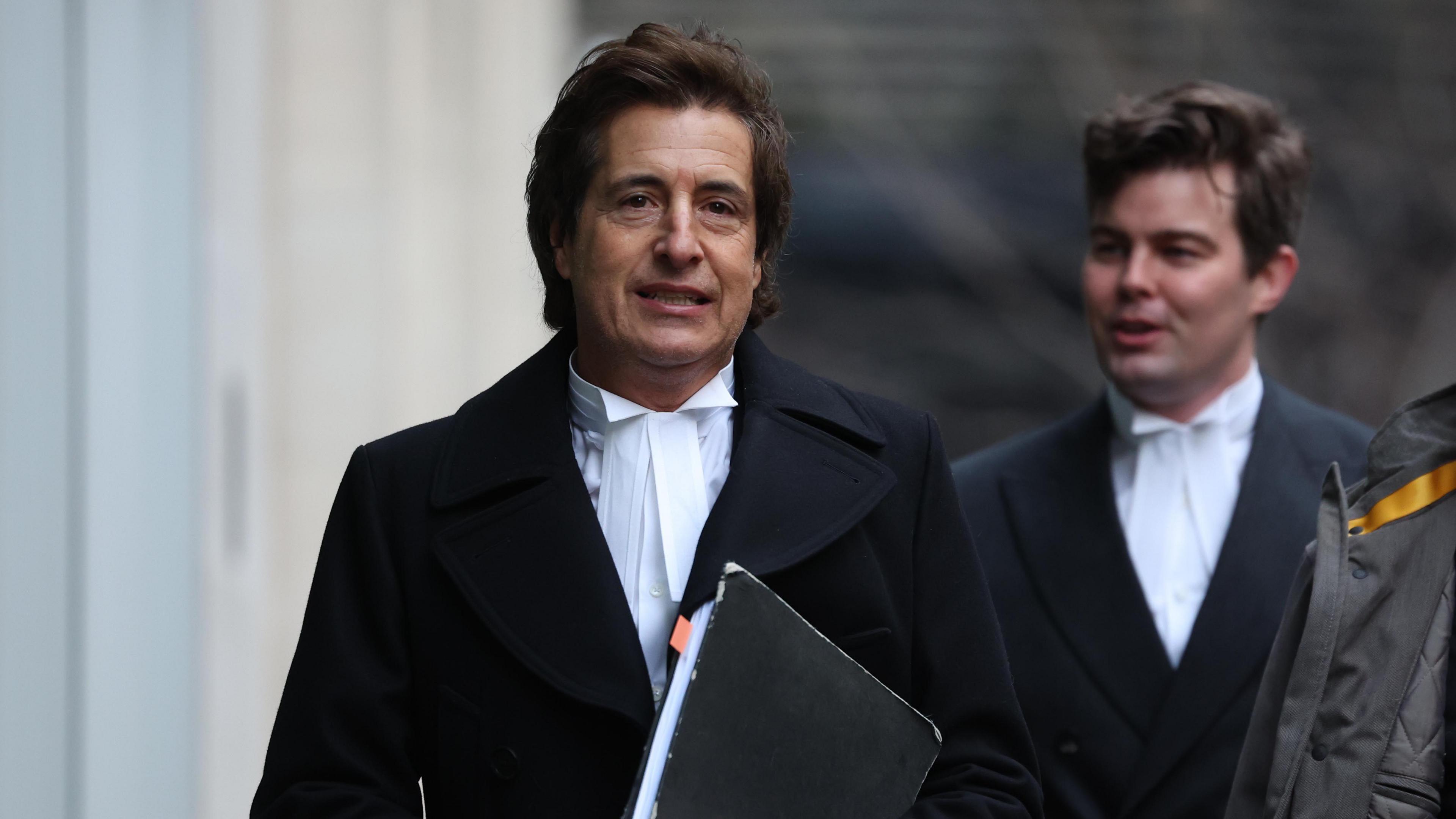 Prince Harry's barrister David Sherborne arrives at the Royal Courts of Justice in London, wearing a white shirt and black coat and carrying a folder of papers