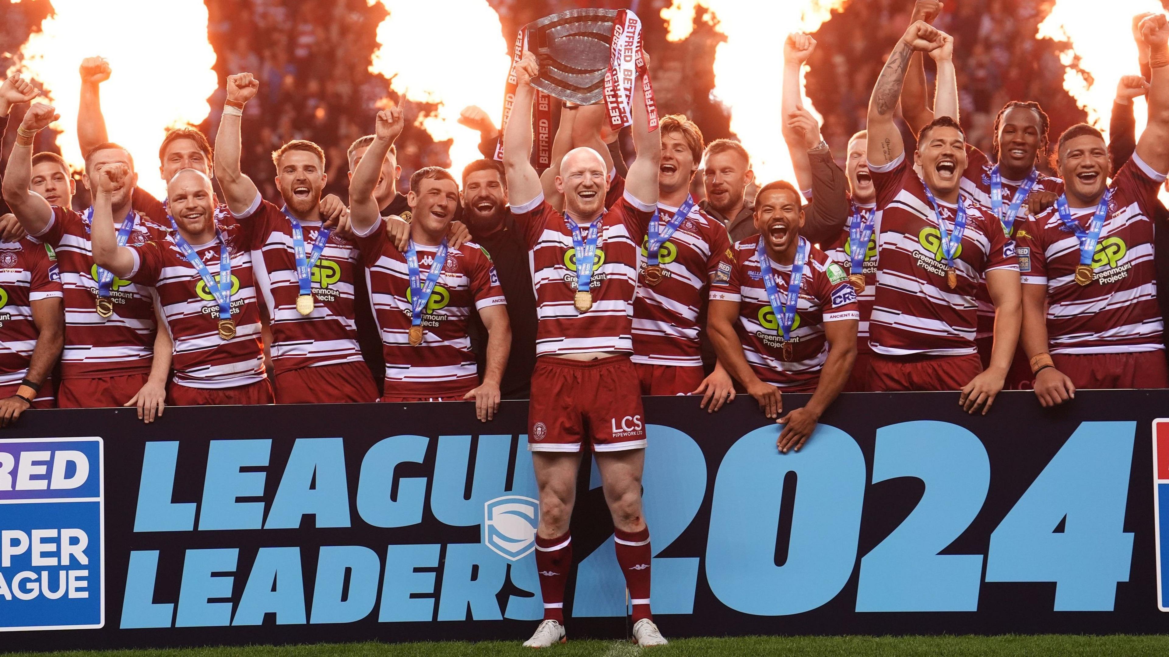 Wigan captain Liam Farrell lifts the League Leaders' Shield in front of his team-mates