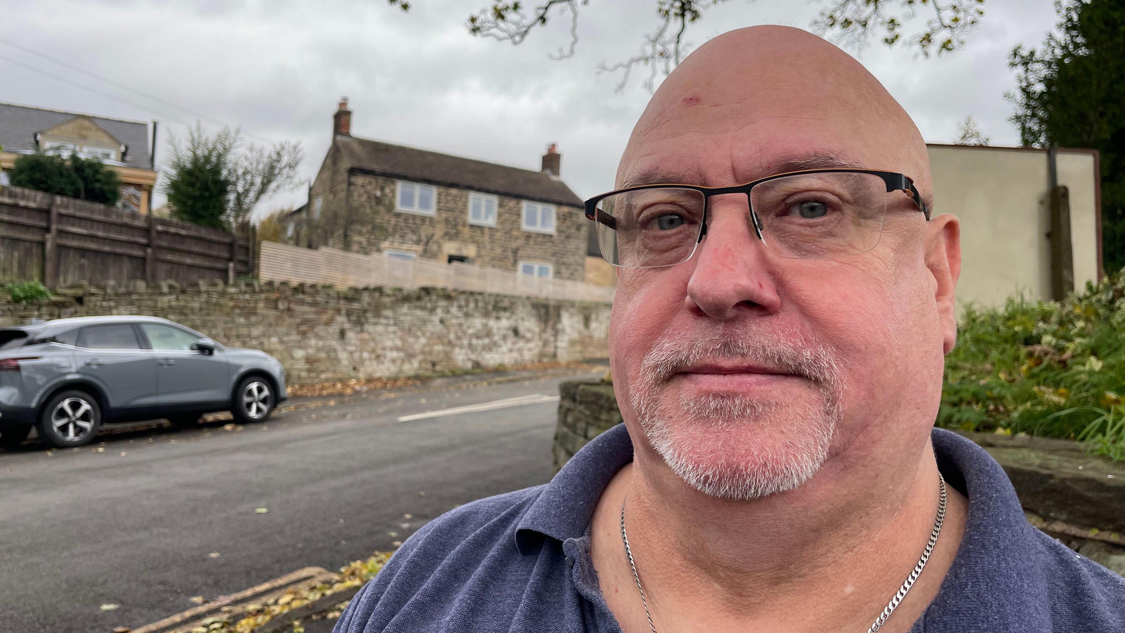 Bald man in blue shirt in front of road