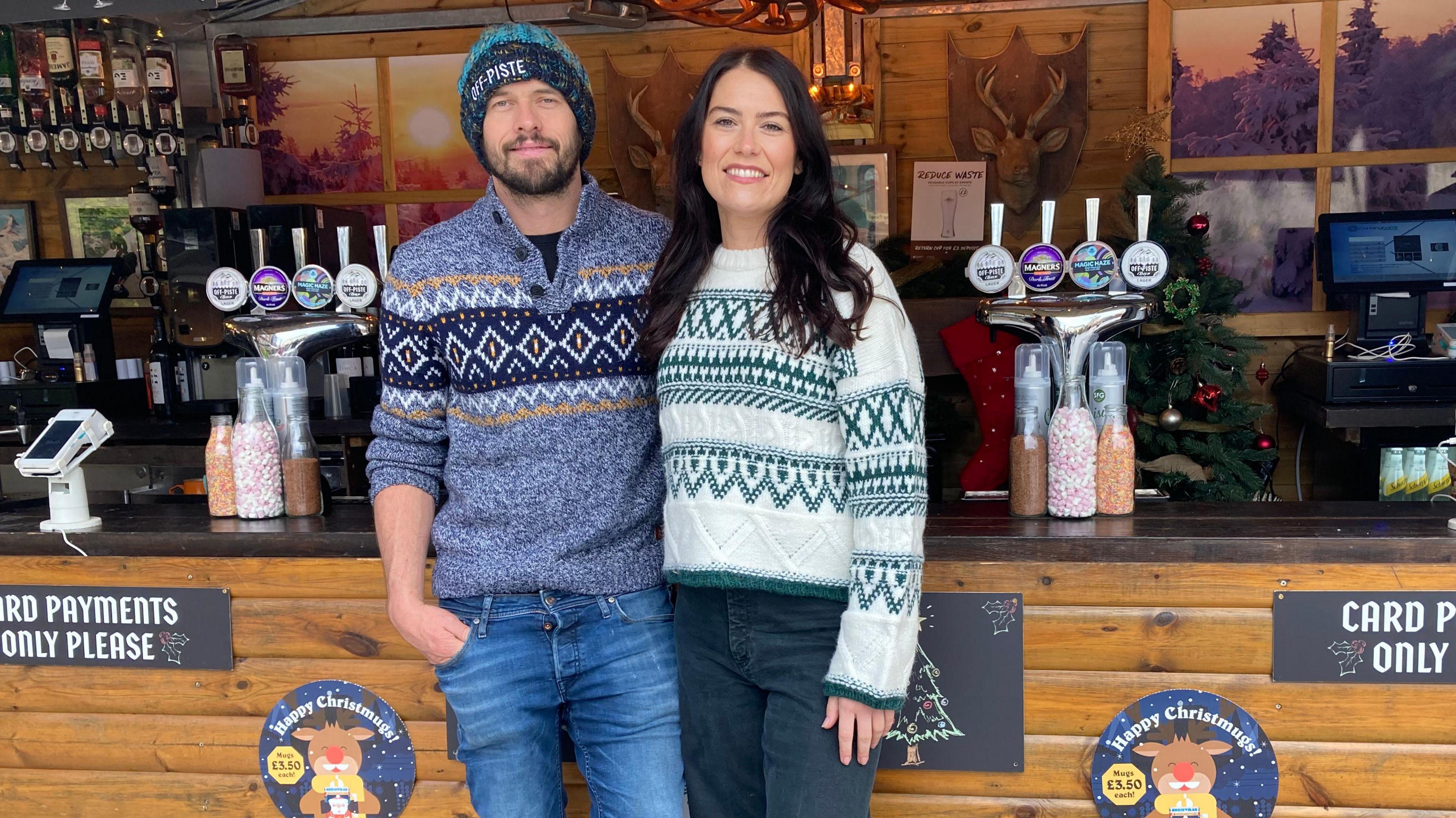 Abbey Matthews and her partner Kyle standing in front of one of their Bar At Yours stalls