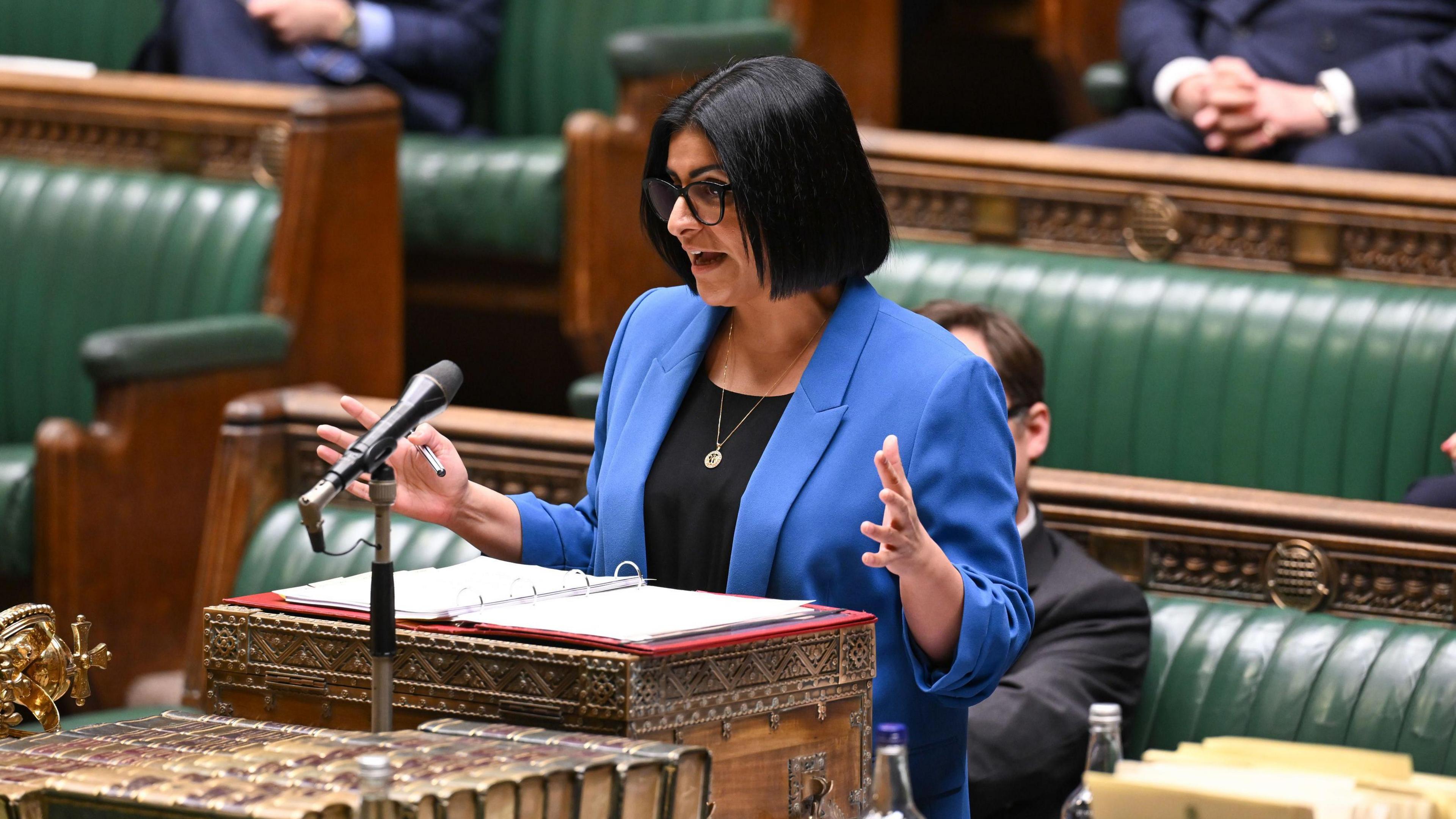 Sekretarja e Brendshme Shabana Mahmood u njofton deputetëve në Dhomën e Komunave në Londër një ndryshim të rregullave për migracionin e ligjshëm. Ajo mban syze me kornizë të errët dhe një xhaketë blu mbretërore mbi një bluzë të zezë.