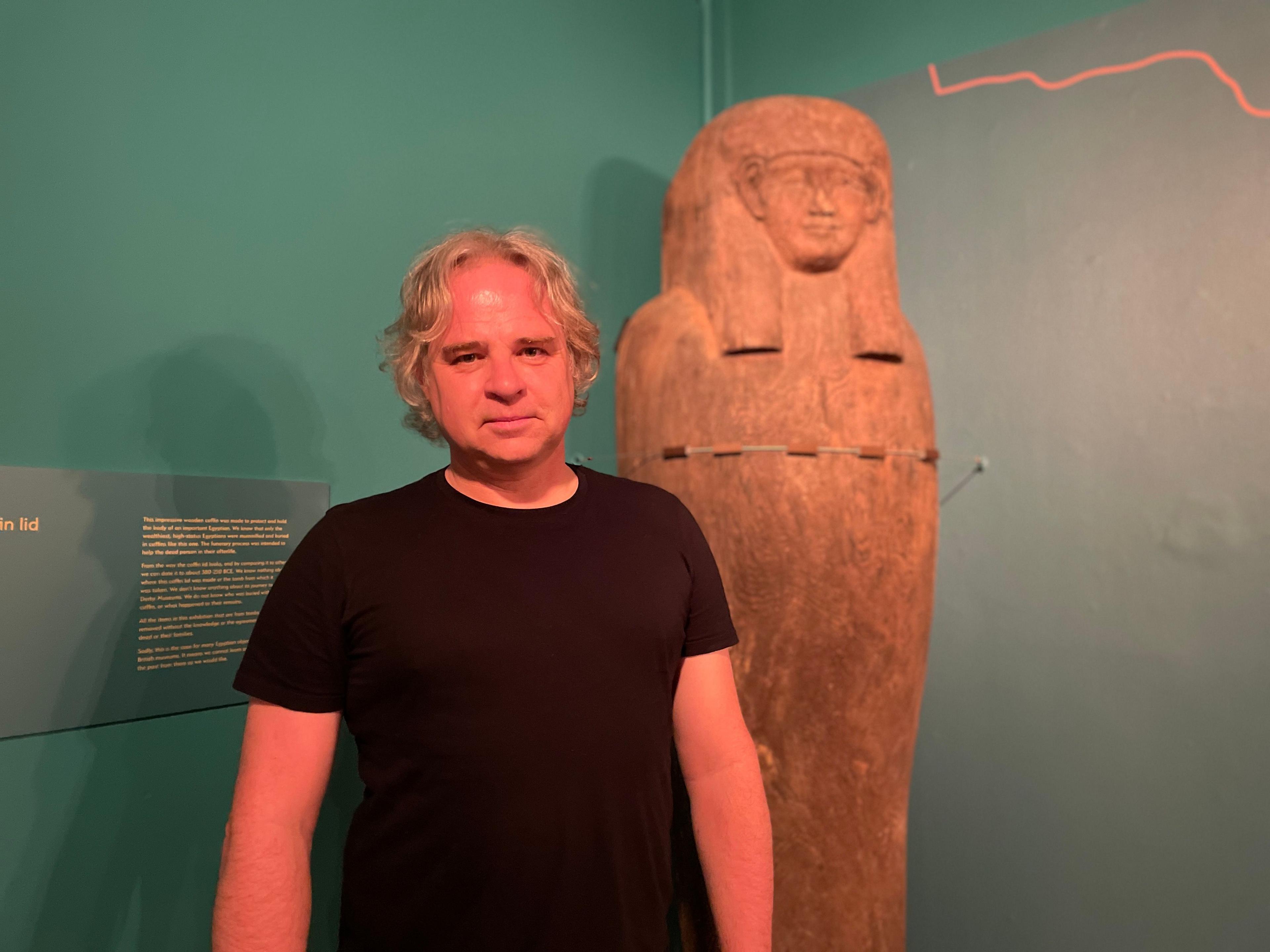 Man standing next to sarcophagus in a museum