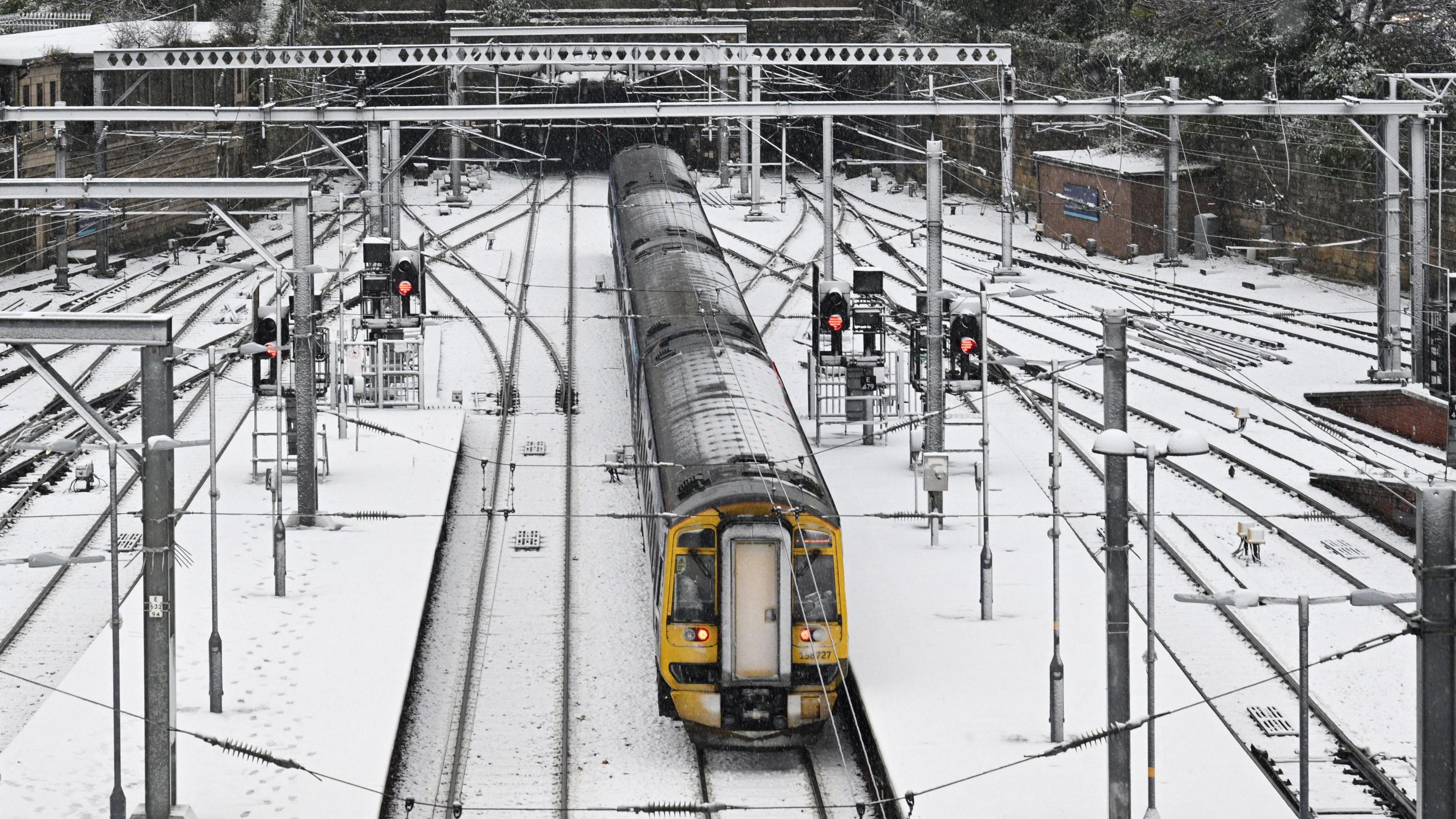 A train pulls out of a station covered in snow