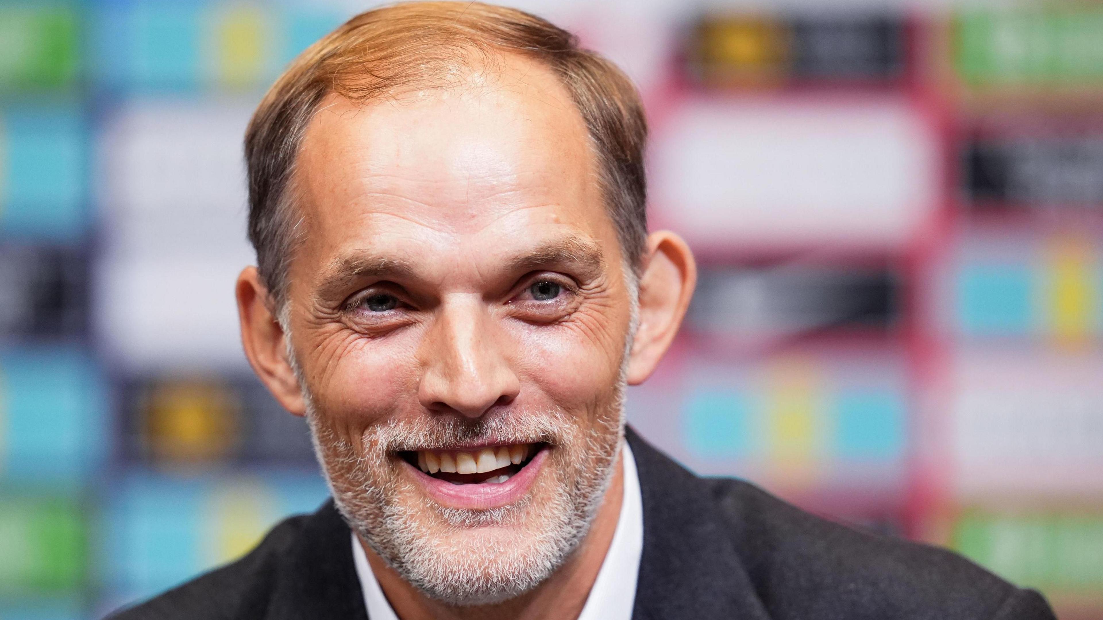  German manager Thomas Tuchel smiles in a grey blazer.