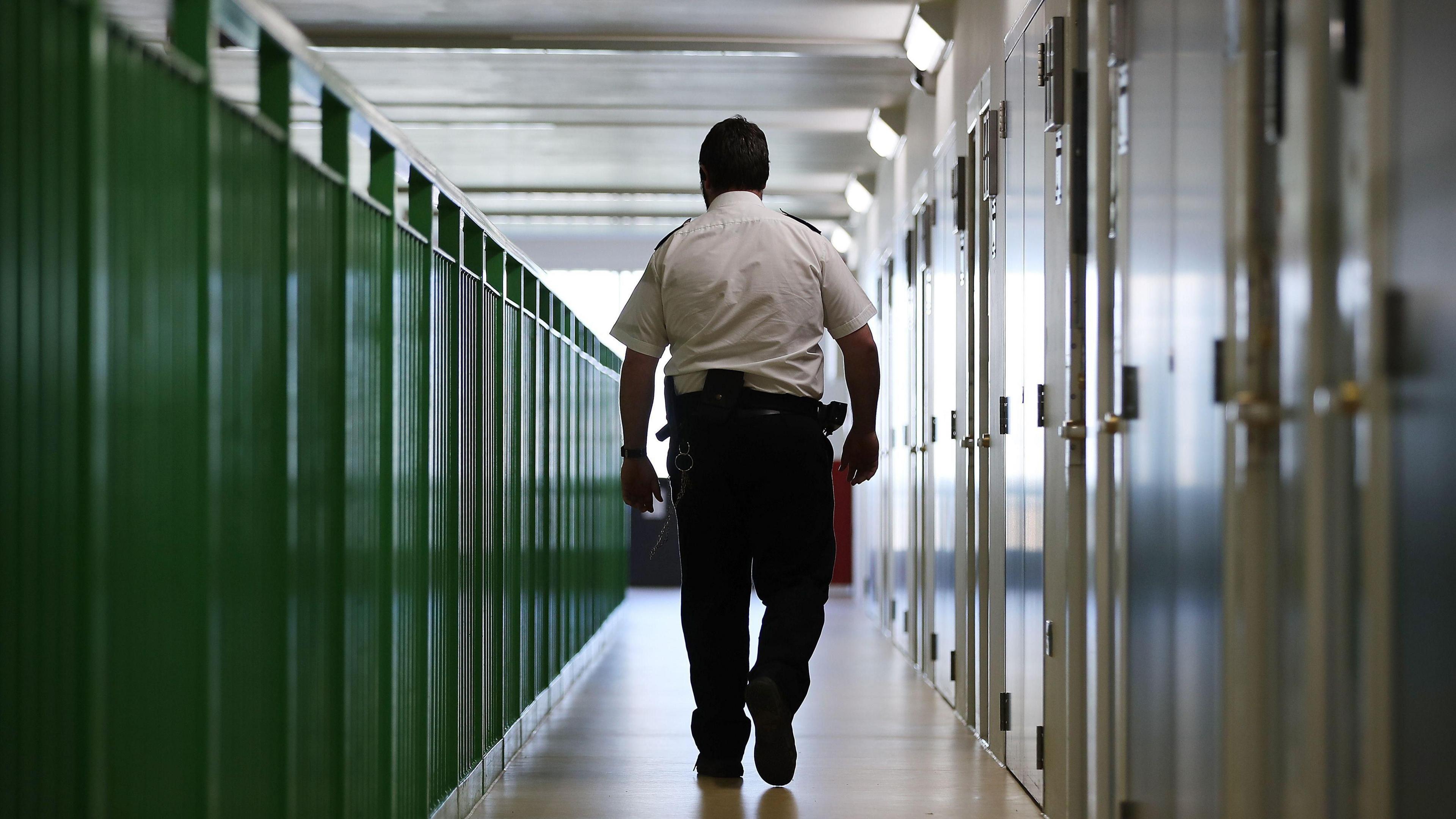 A prison guard walks through a cell area at a prison