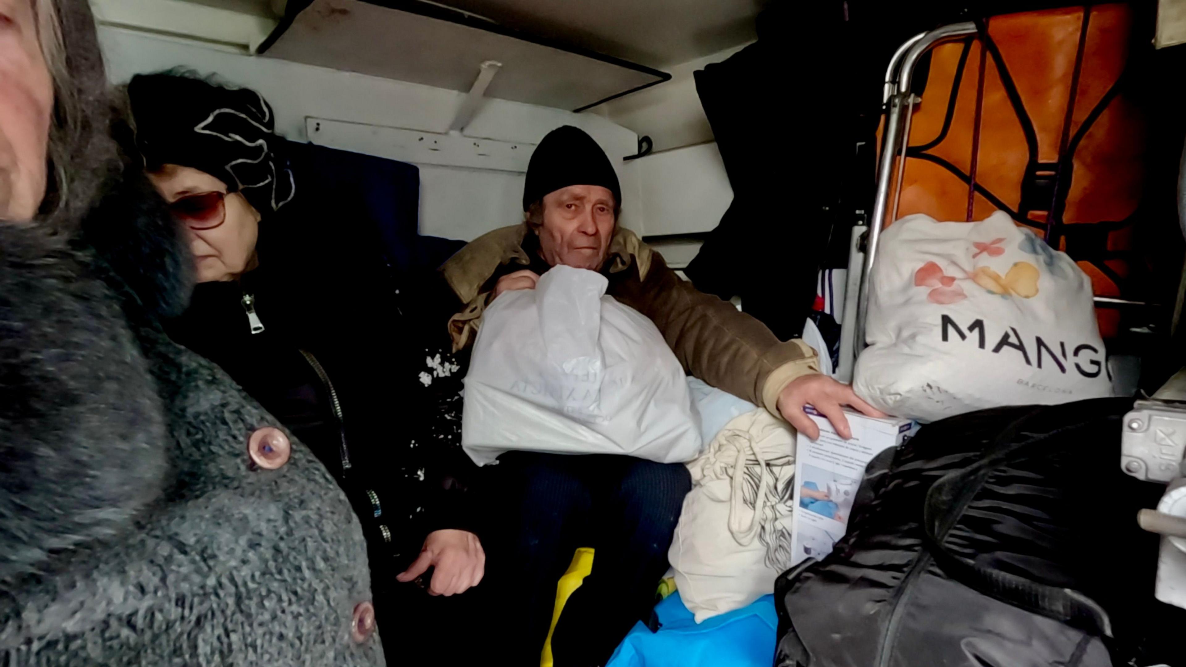 Two women and a man, all Pokrovsk residents, sit in the back of the van surrounded by bags of belongings 