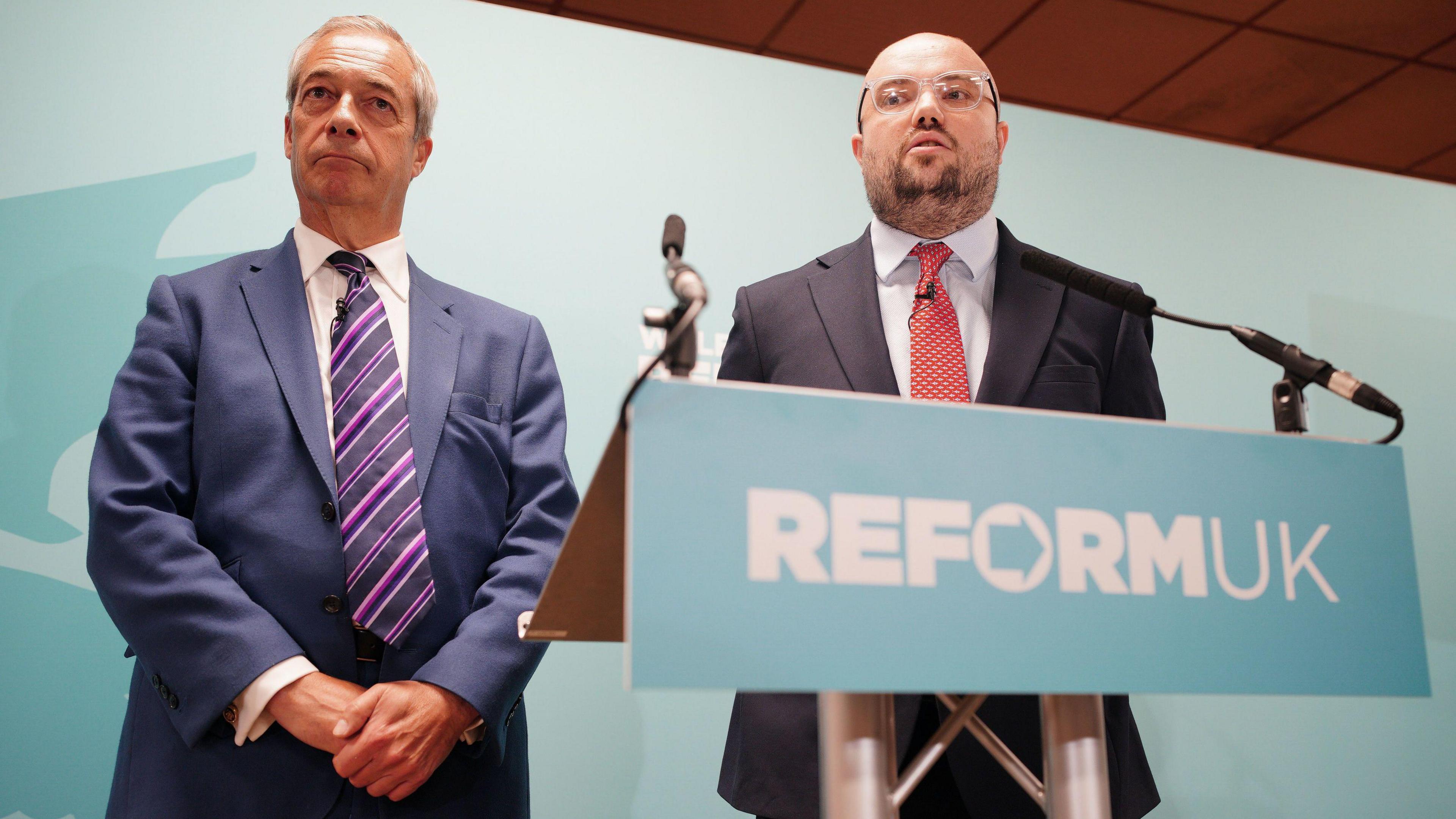 Reform UK leader Nigel Farage looks on as Llyr Powell (right), who has been chosen as the party candidate for the upcoming Caerphilly Senedd by-election, speaks during a press conference in Caerphilly