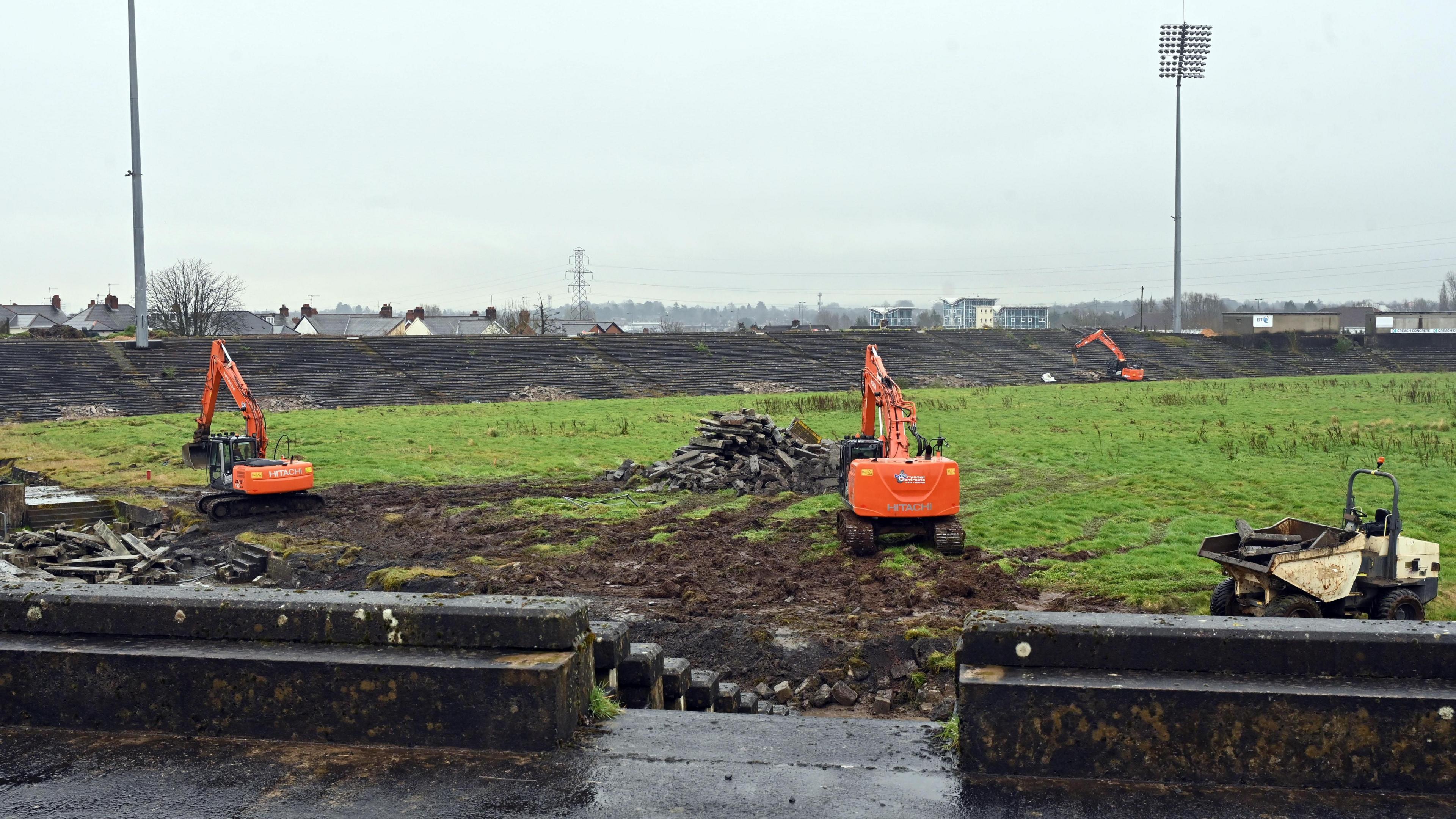 Three orange diggers working on the grounds of Casement Park.