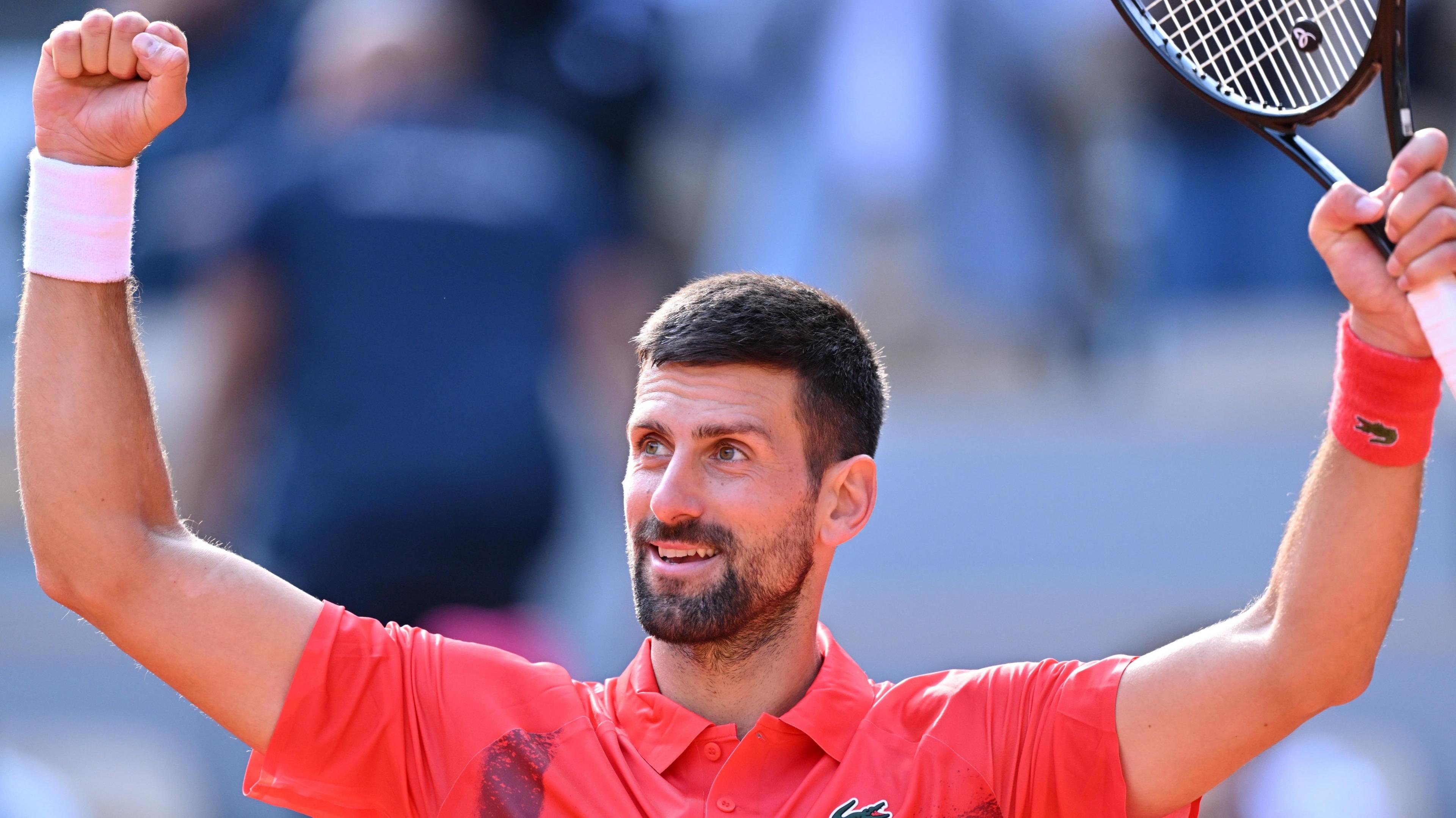 Novak Djokovic raises his arms in celebration after victory over Cameron Norrie at the French Open
