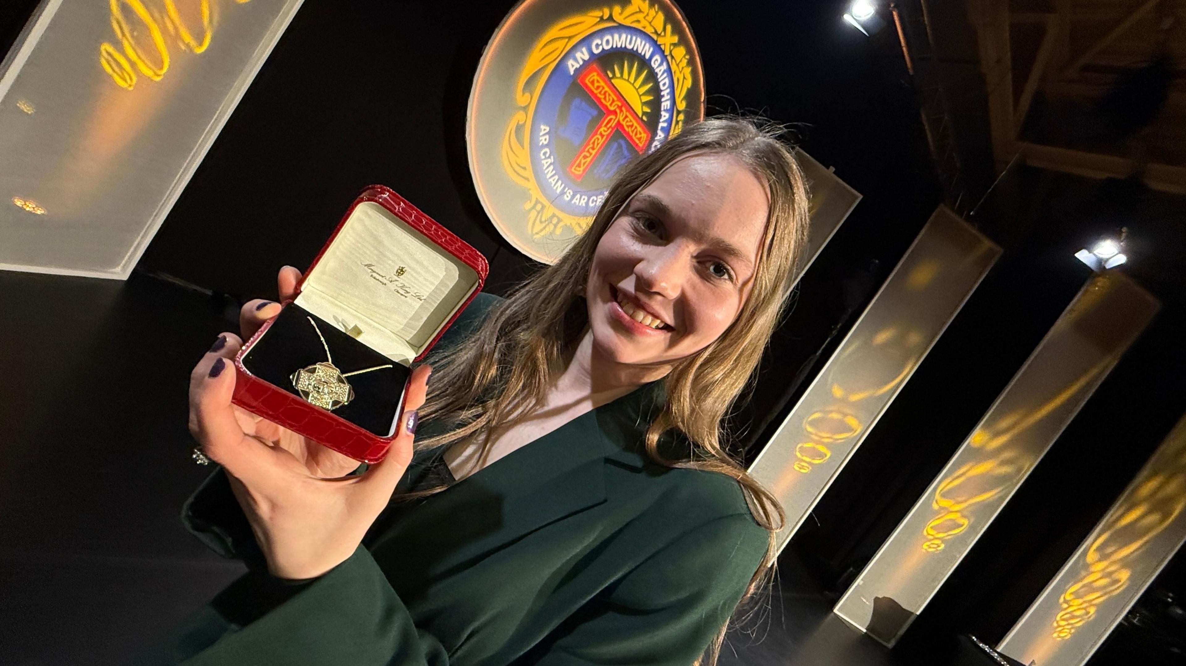 Màiri Callan 's Bonn Òir an t-Seann Nòis na làimh aig a' Mhòd Nàiseanta Rìoghail anns a' Ghearasdan