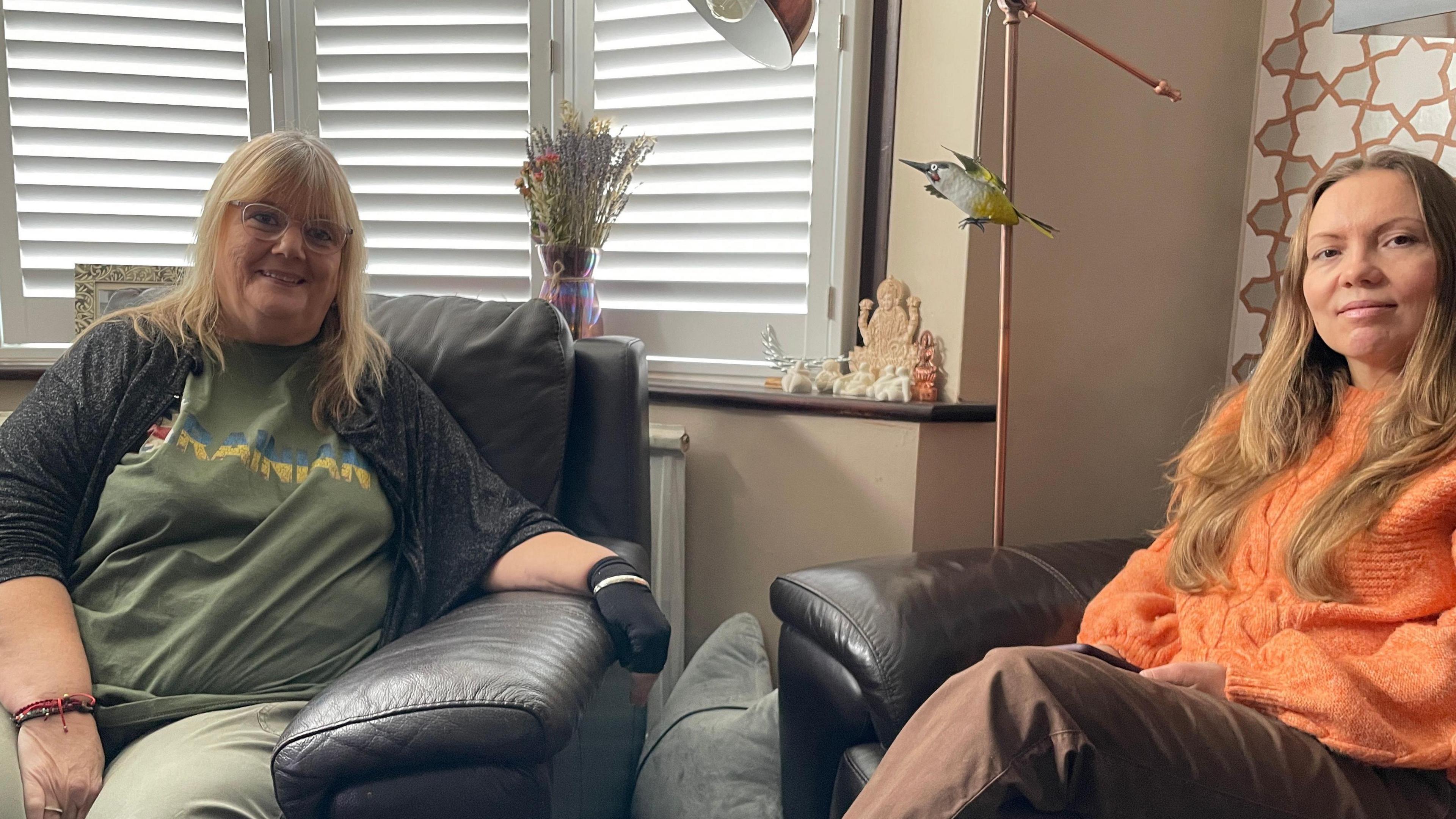 Lauren Kilbey and Olena Zakharova sitting in leather armchairs in a house.