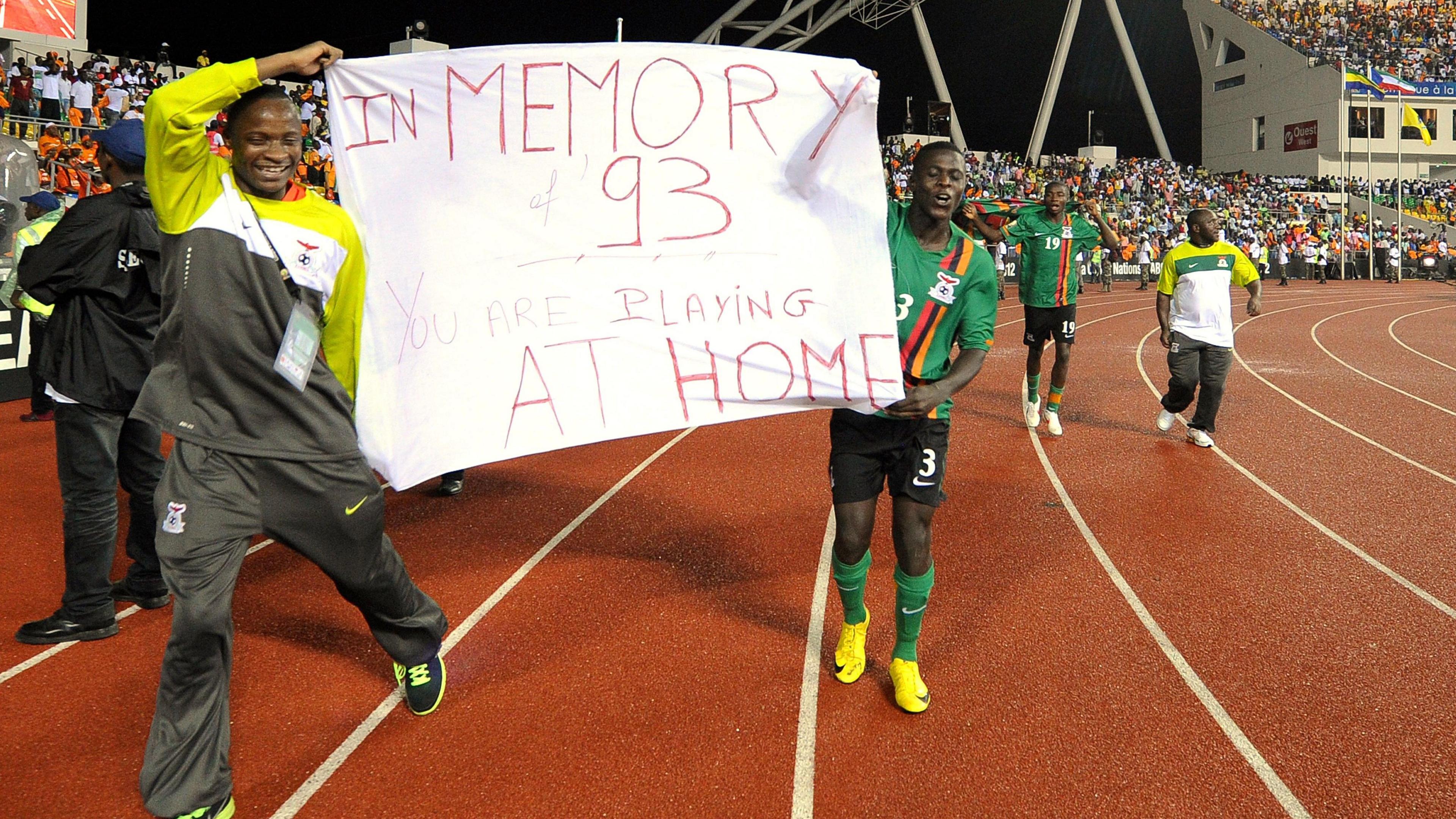 Zambia's players take a lap of honour holding a banner referencing the team of 1993