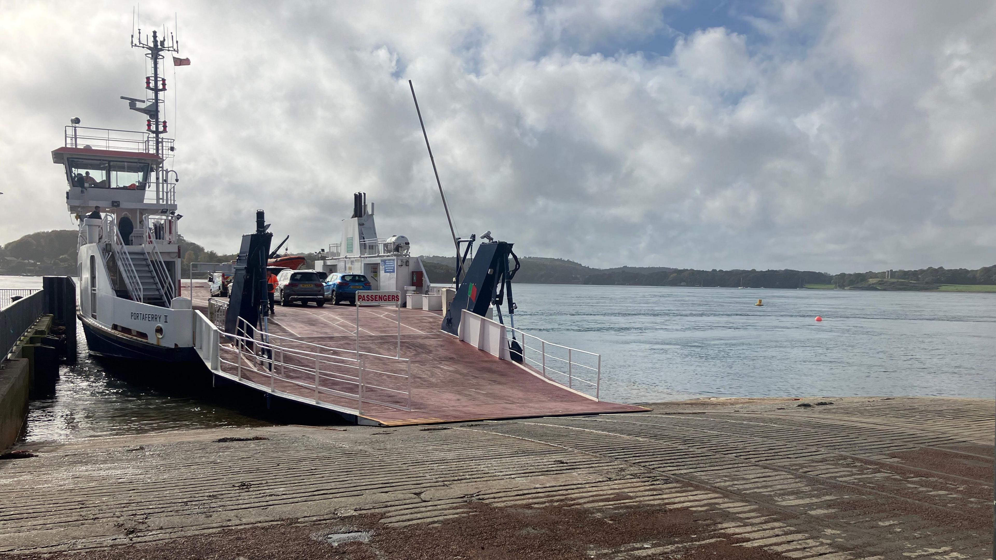 A docked car ferry with a blue car and a grey car onboard  