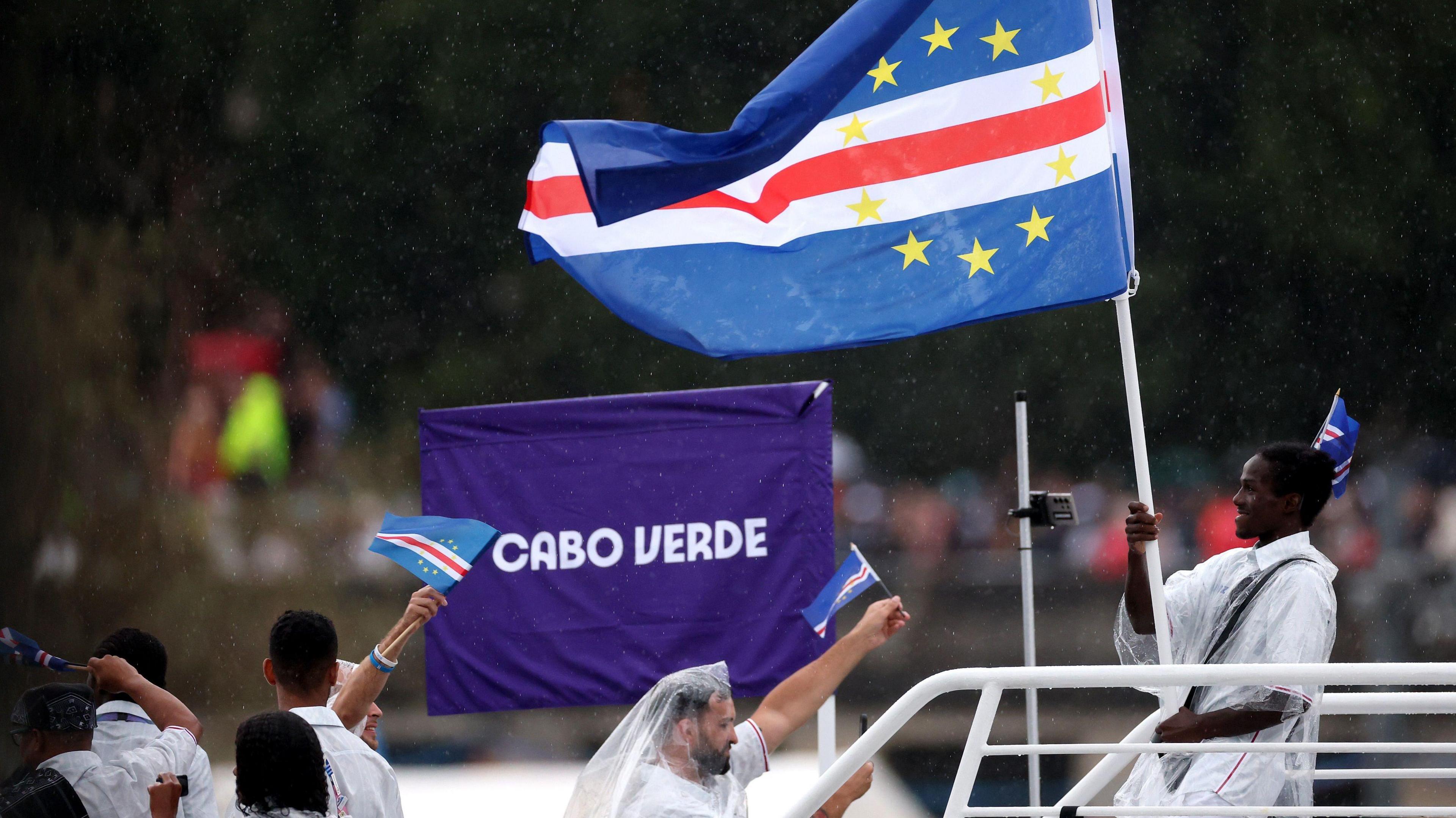 David de Pina holds the Cape Verdean flag on a boat during the opening ceremony for Paris 2024