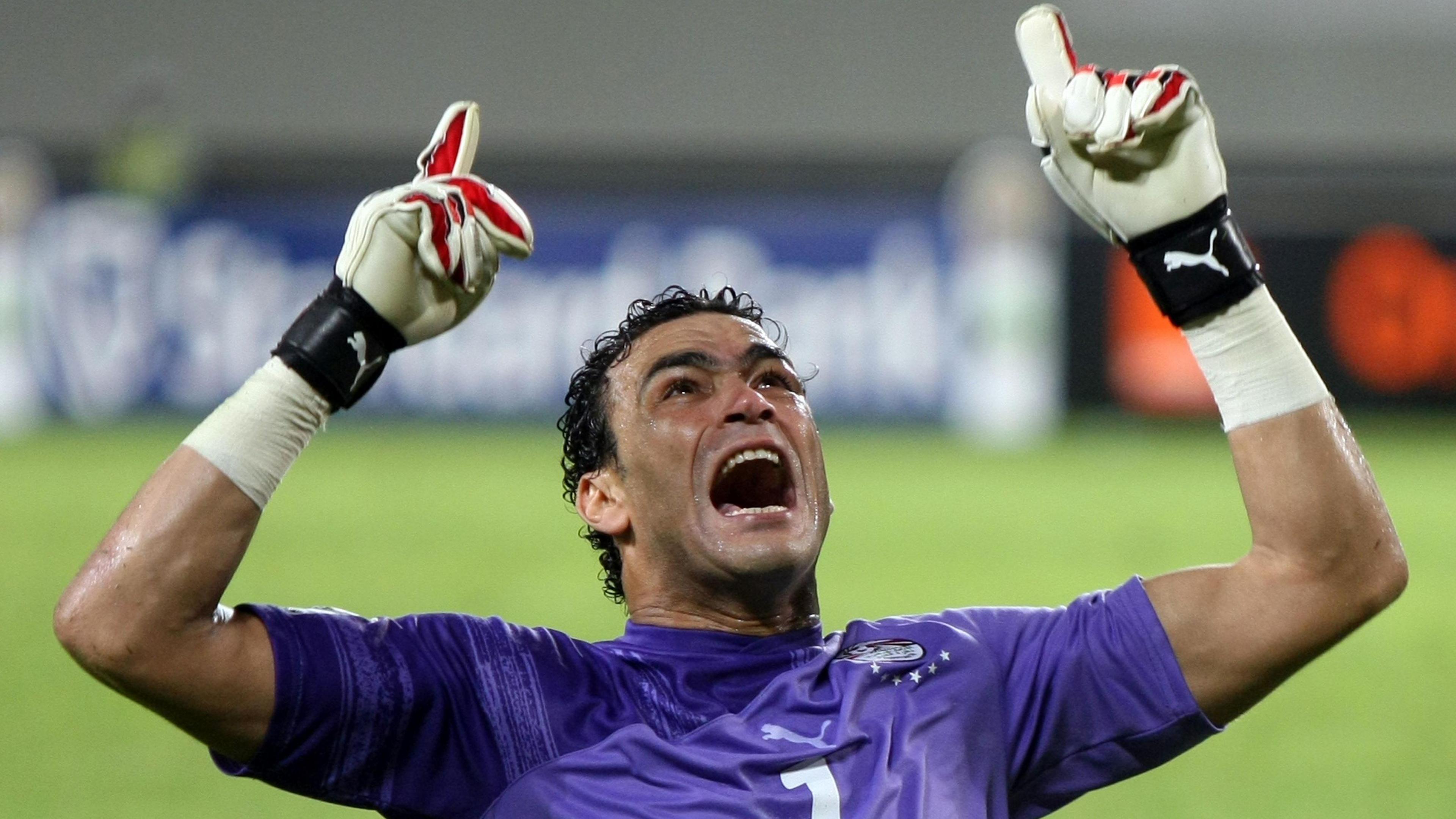 Egypt goalkeeper Essam El-Hadary wears a short-sleeved purple shirt, raises both arms into the air, points upwards and screams in delight after winning a semi-final against Algeria at the 2010 Afcon.