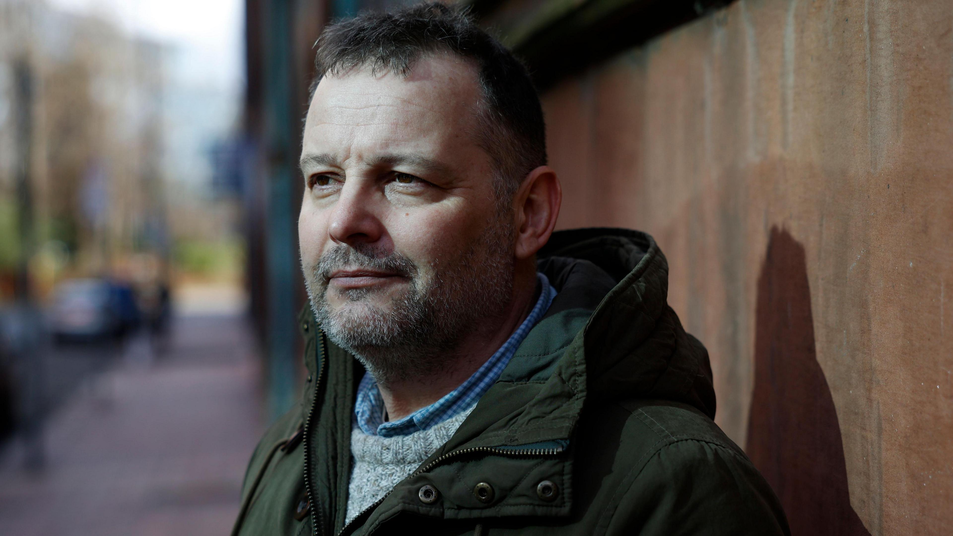 Keith Hinchliffe standing on the street, wearing a jacket and sweater 