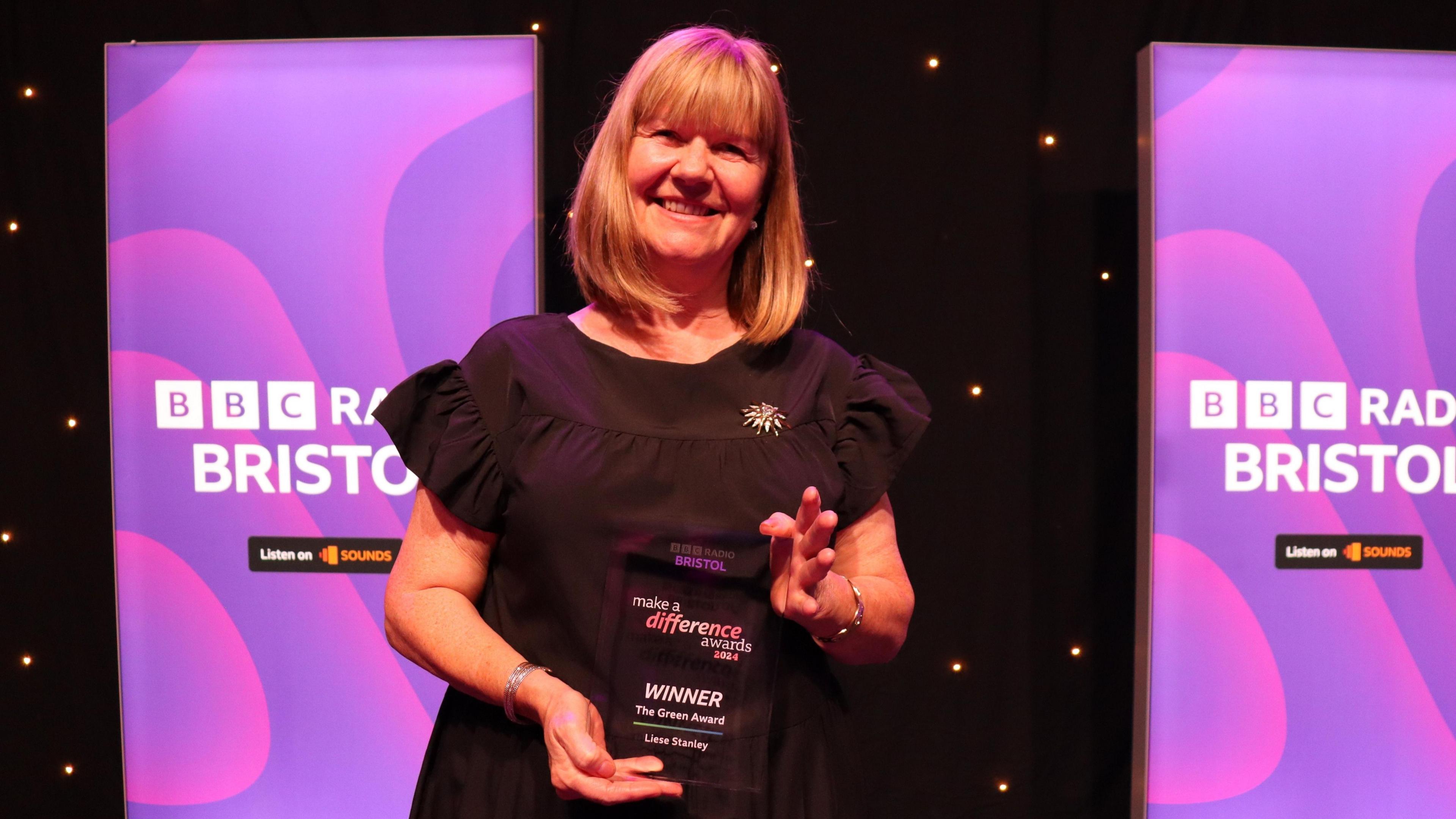 Liese Stanley holding her award on a stage.