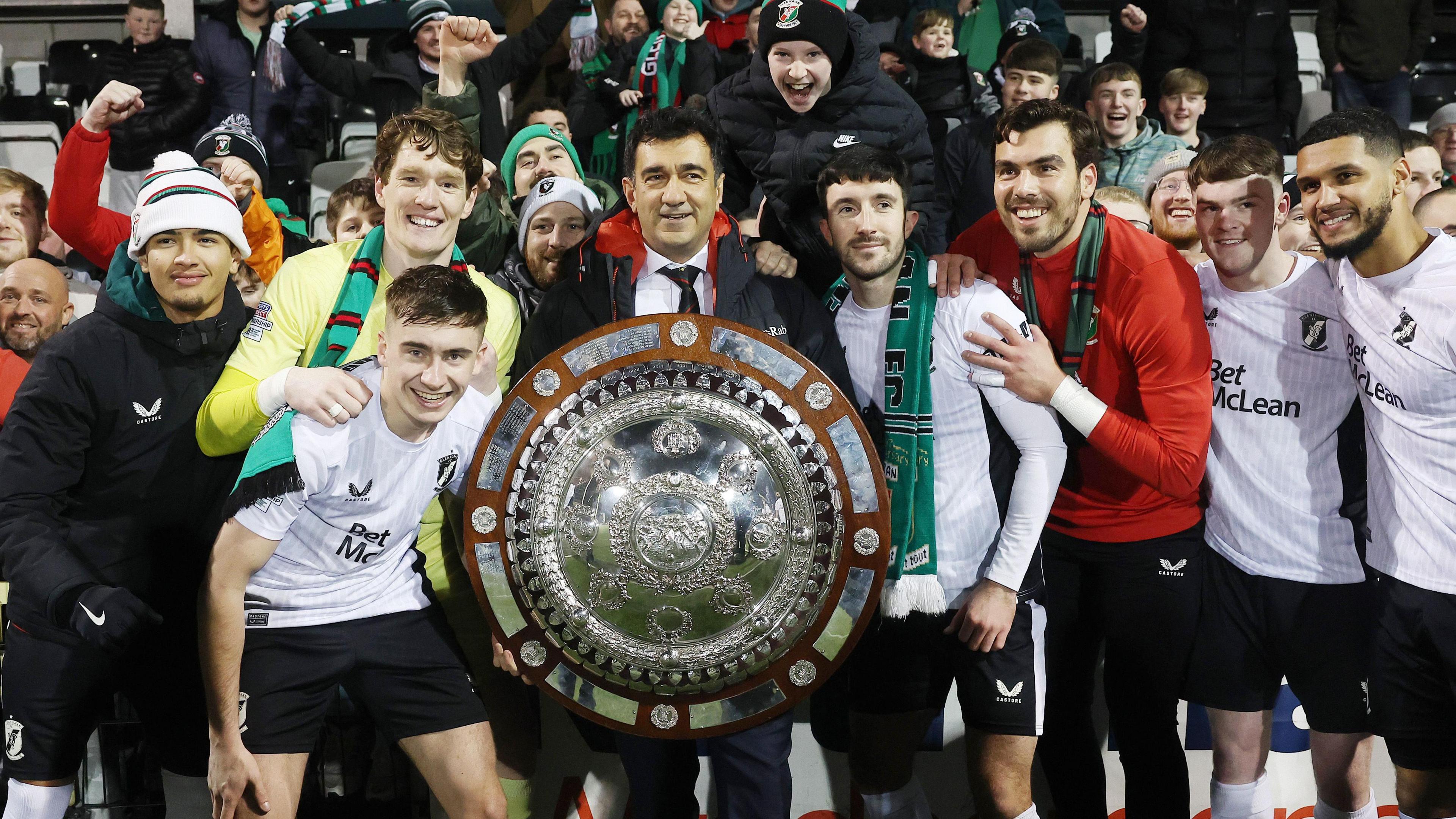 Ali Shams Pour celebrates with players after winning the County Antrim Shield