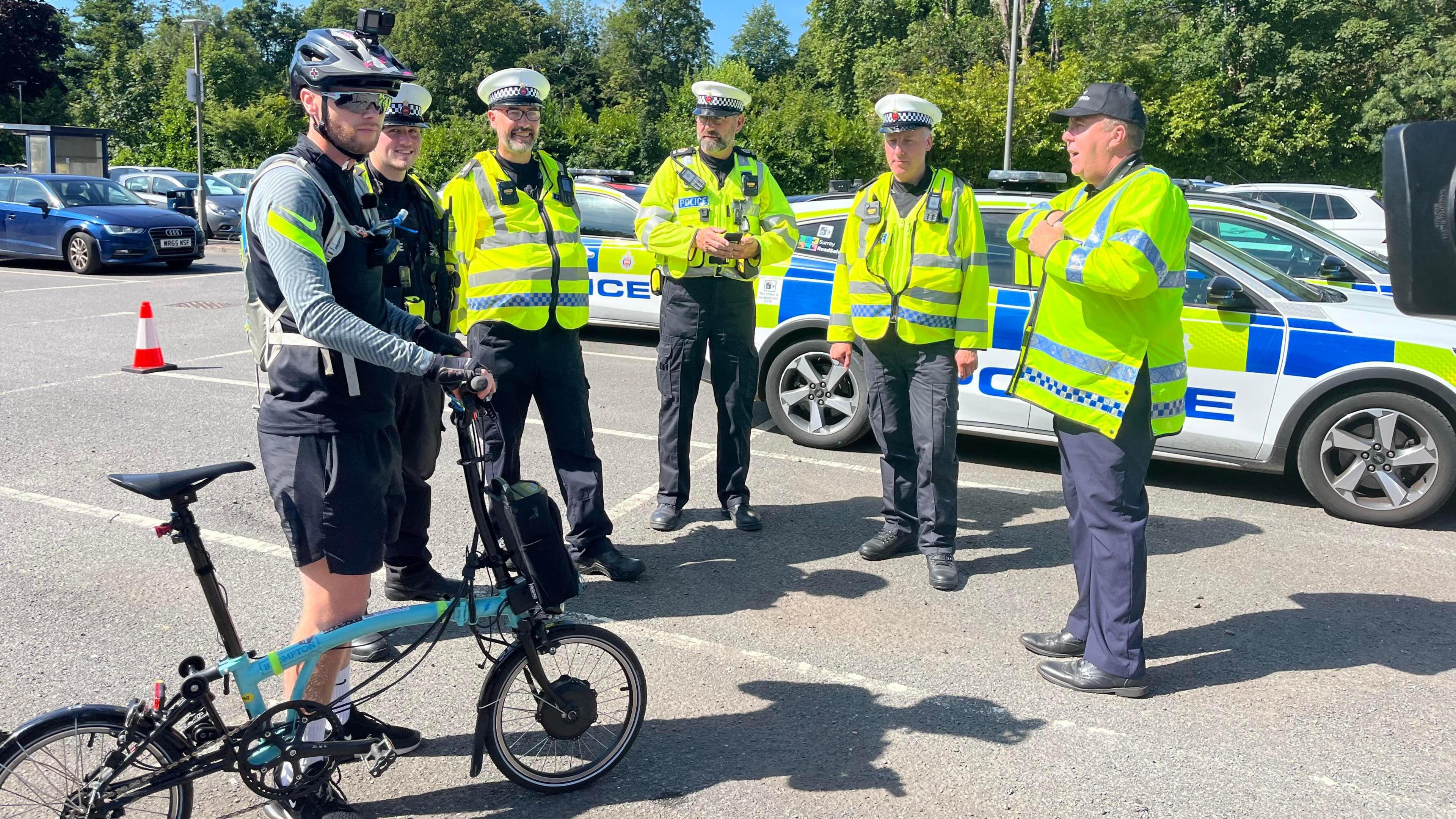 A group of Surrey Police officers in uniform, one officer wearing cycling gear, as part of the operation to tackle the issue of drivers using mobile phones 